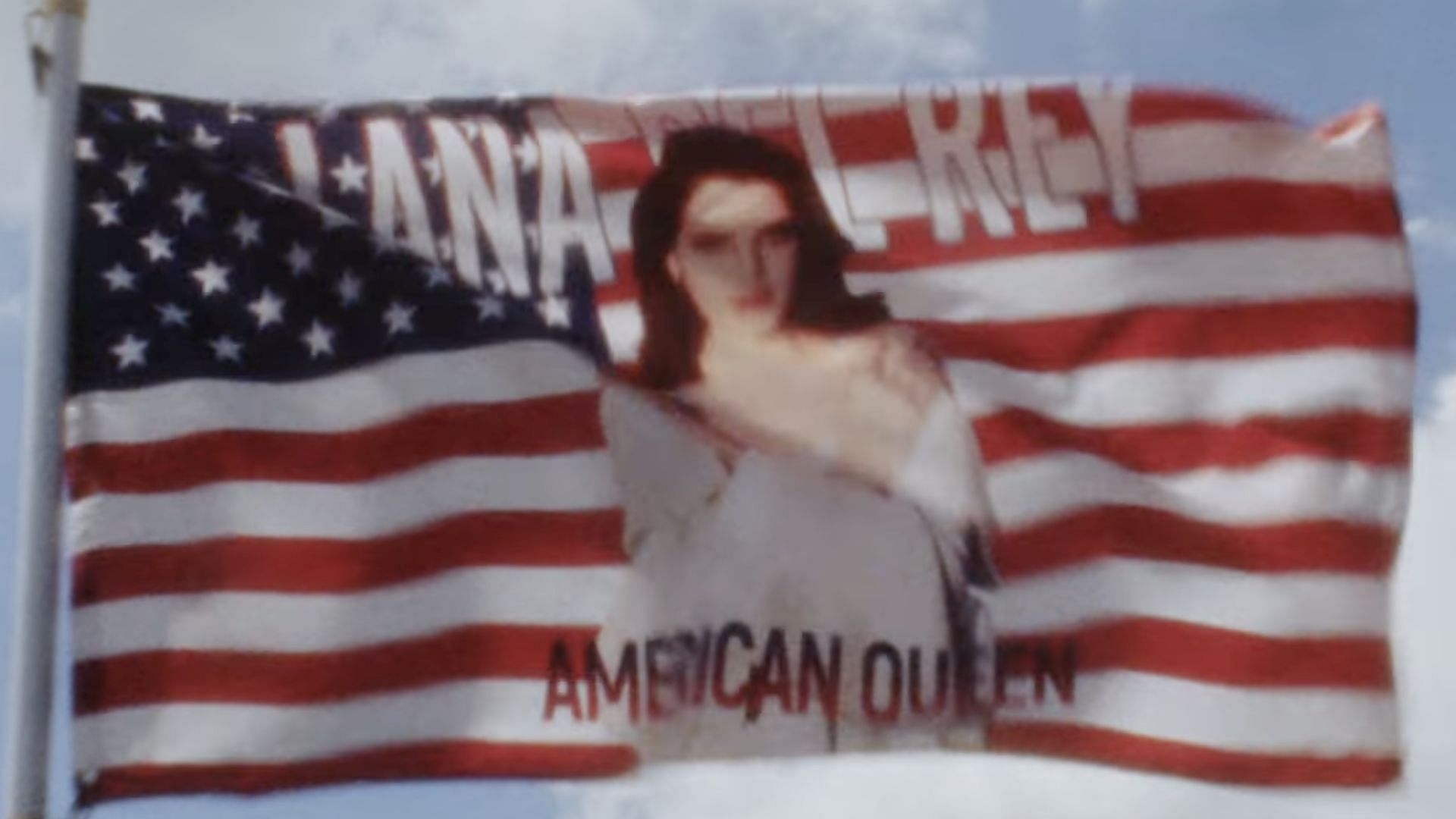 A screenshot of an American Flag with Lana Del Rey&#039;s picture captioned as &quot;American Queen&quot; in the music video for &#039;Tough&#039; (Image via YouTube/@ quavohuncho5077)