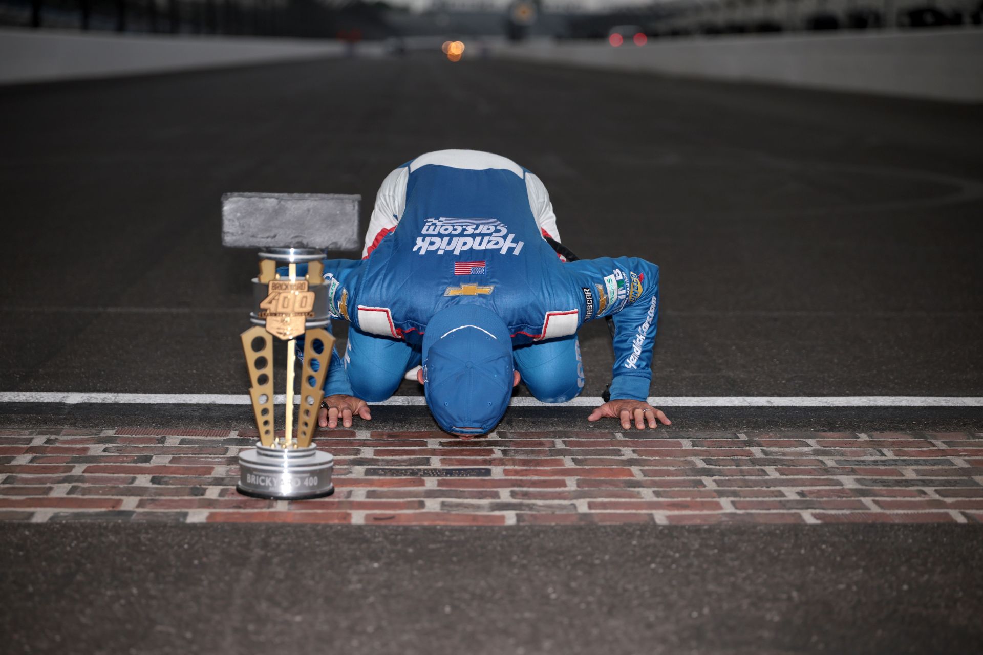 Kyle Larson, driver of the #5 HendrickCars.com Chevrolet, kisses the yard of bricks after winning the NASCAR Cup Series Brickyard 400 at Indianapolis Motor Speedway on July 21, 2024 in Indianapolis, Indiana. (Photo by James Gilbert/Getty Images)