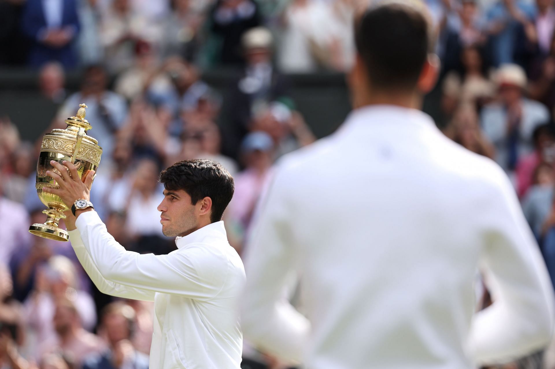 Novak Djokovic looks on as Carlos Alcaraz raises the Wimbledon trophy (image source: GETTY)