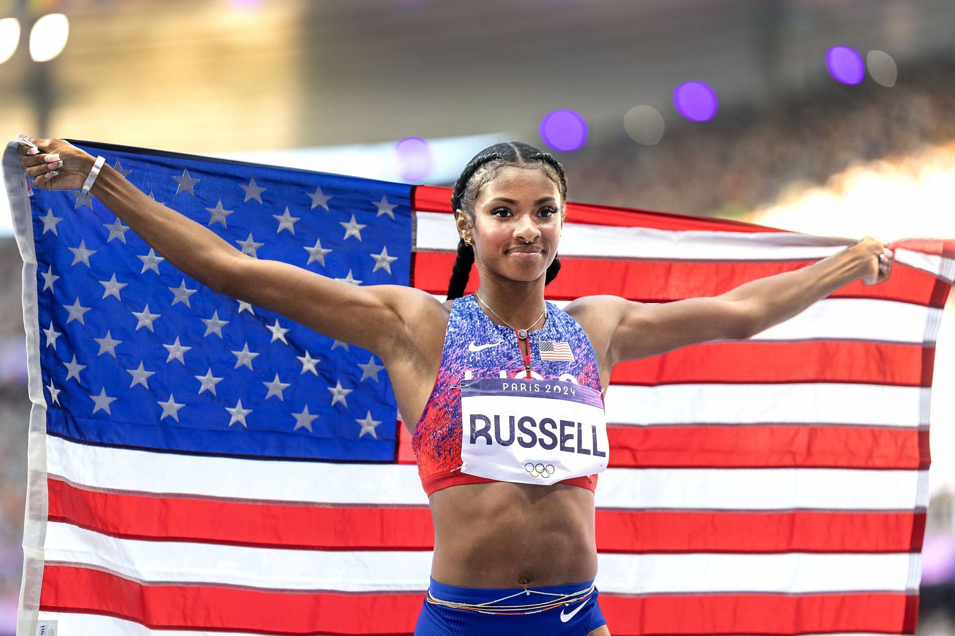 Russell with the American flag after winning the women&#039;s 100m hurdles event at the Paris Olympics 2024 [Image Source: Getty]