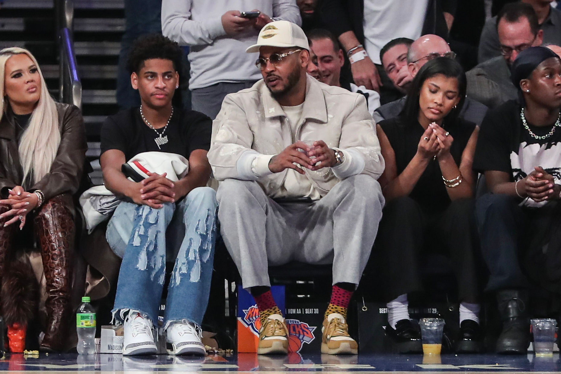 Former NBA player Carmelo Anthony sits with his son Kiyan Anthony at a game at Madison Square Garden. Photo Credit: Imagn