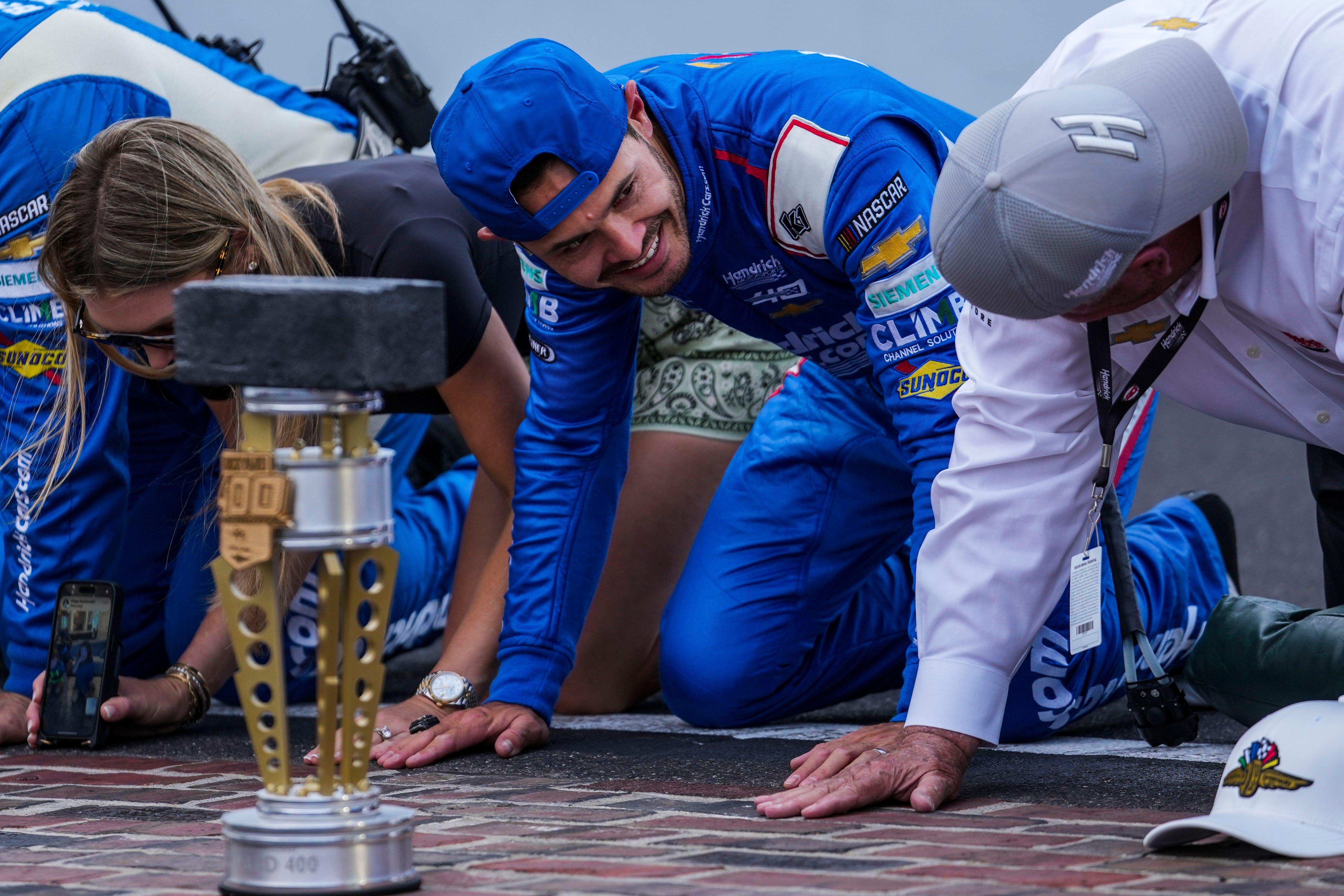 Kyle Larson (5) looks over at the owner of Hendrick Motorsports, Rick Hendrick, during the kissing of the bricks following the Brickyard 400, Sunday, July 21, 2024, at Indianapolis Motor Speedway | Imagn