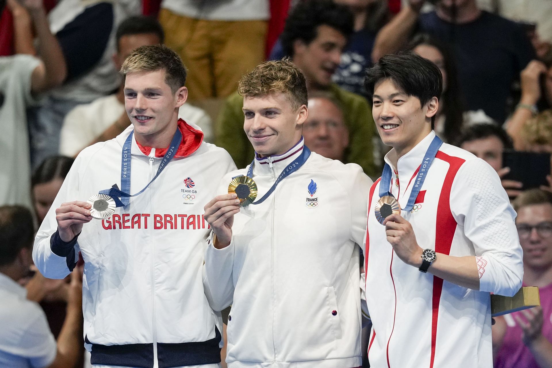 French swimmer Leon Marchand with silver medalist Duncan Scott of Great Britain and bronze medalist Wang Shun of China at the medal ceremony of the Men&#039;s 200m Individual Medley at the 2024 Paris Olympics [Image Source: Getty]