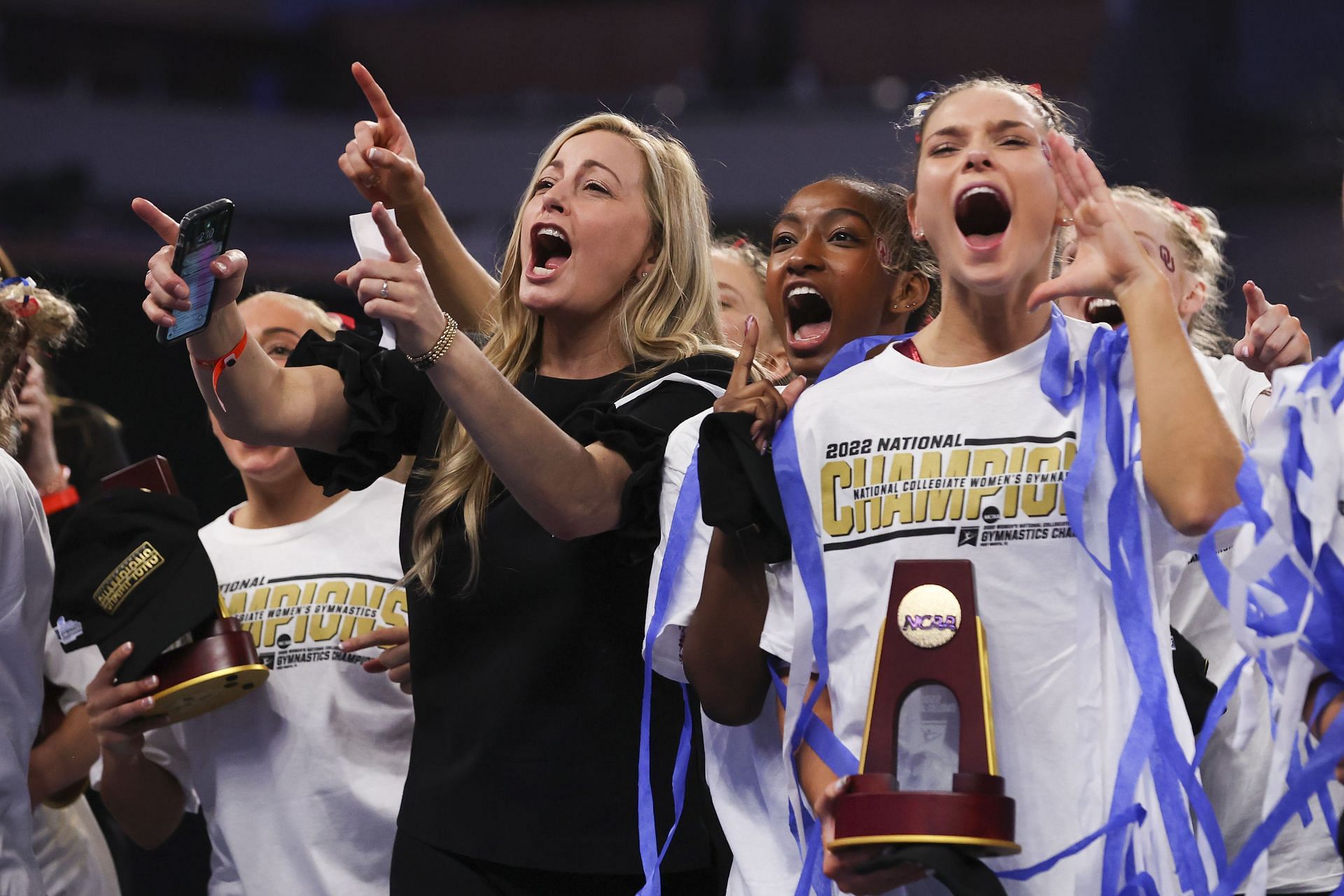 K.J. Kindler (in black) celebrates the 2022 NCAA Championships win with the Oklahoma Sooners