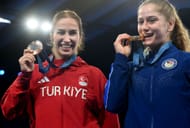 Buse Cavusoglu Tosun of Turkiye (red) and Amit Elor (blue) of the US pose for a photo at the end of the Wrestling Women's Freestyle 68kg at the Olympic Games 2024 in Paris, France. (Photo via Getty Images)