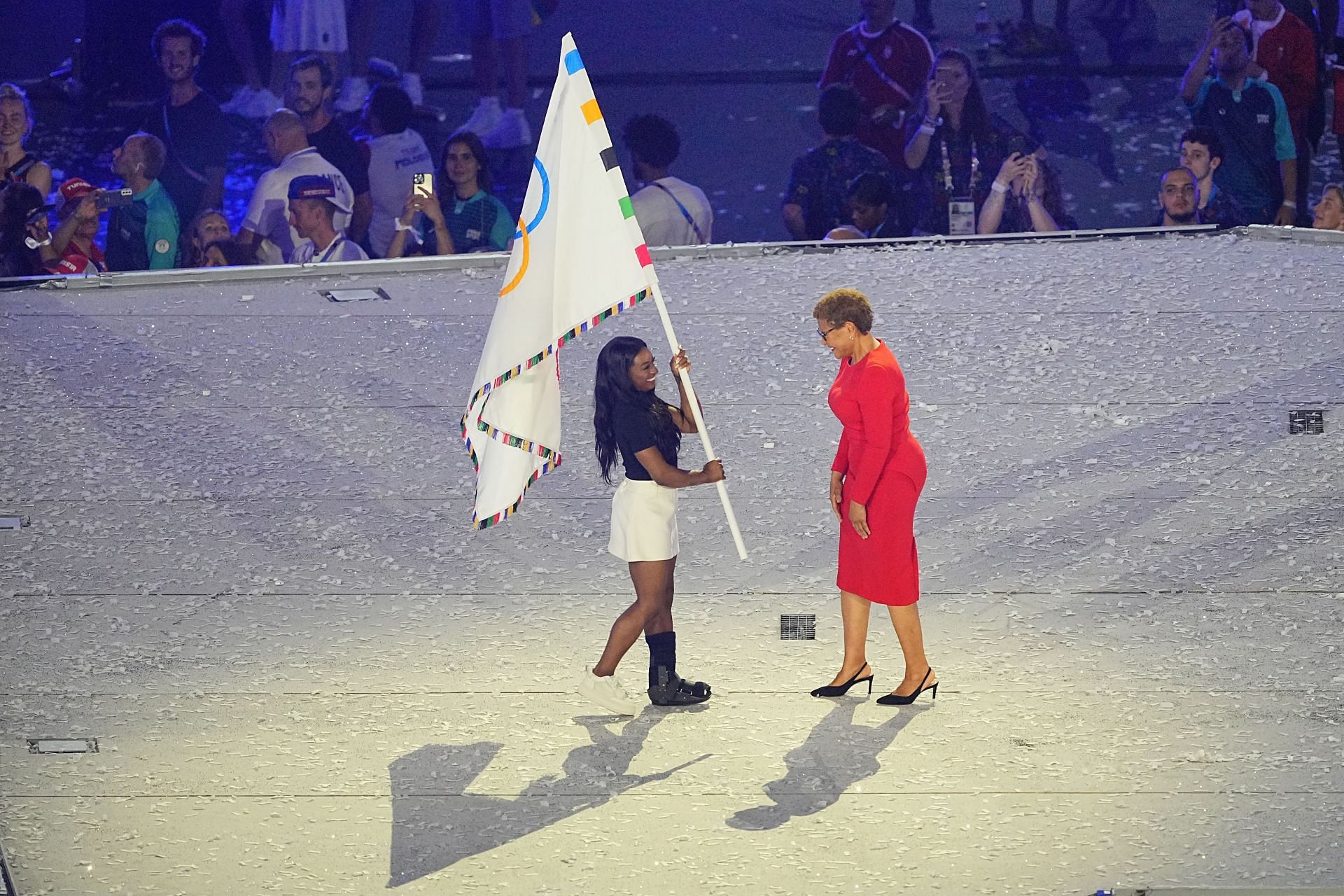 Simone Biles and Karen Bass with the Olympic flag at the closing ceremony of the Paris Olympics - Getty Images