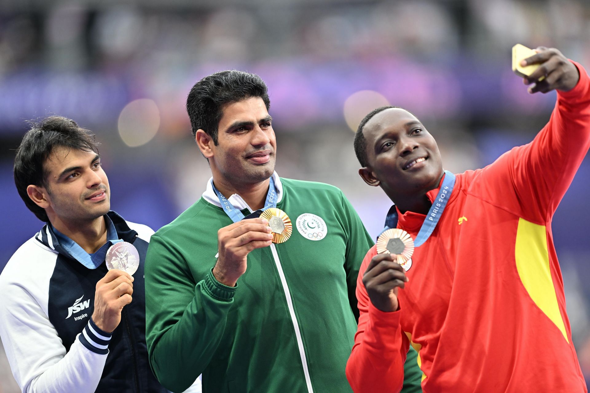 Bronze medalist Anderson Peters of Grenada [R] takes a selfie with Olympic champion Arshad Nadeem from Pakistan [C] and silver medalist Neeraj Chopra [L] of India at the Paris Olympics 2024 [Image Source: Getty]