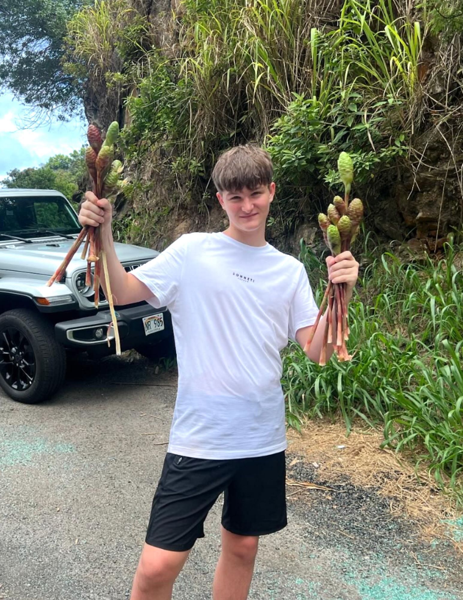 Lucas Bisping holding up plants he collected from the jungle. [Image courtesy: @mikebisping on Instagram]