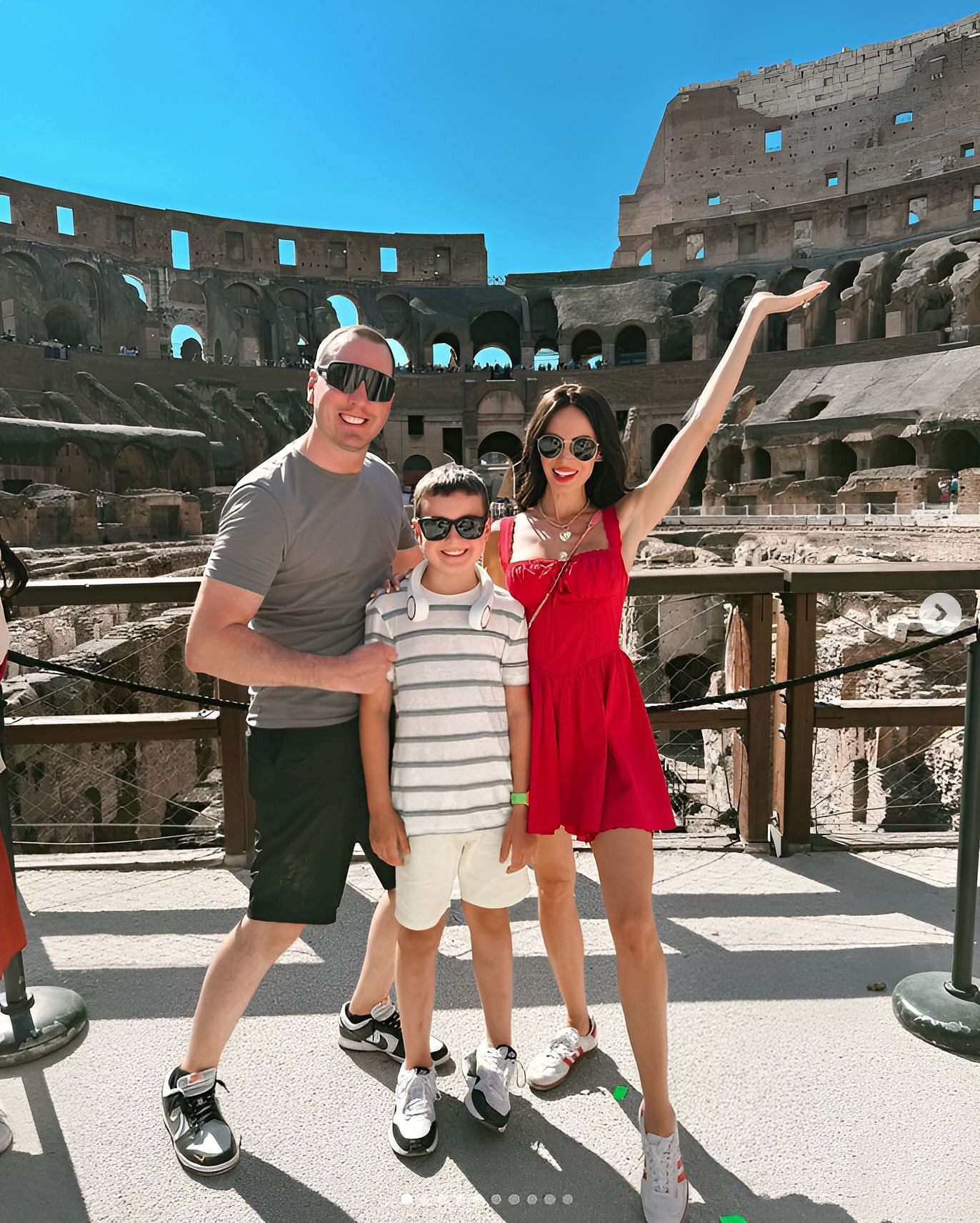 Samantha in a bright red mini dress by Kazo with a Chanel handbag and Adidas Gazelle sneakers, along with Kyle Busch with their son Brexton (IMAGE: Instagram, Samantha Busch)