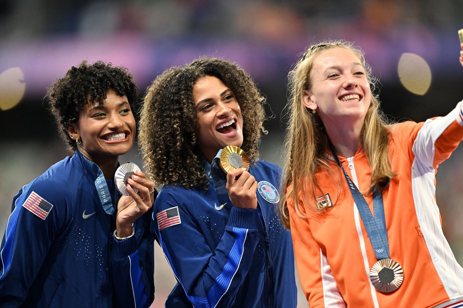 Bronze medalist from the Netherlands Femke Bol [R] posing for a selfie with silver medalist Anna Cockrell [L] and Olympic champion Sydney McLaughlin-Levrone [C] of the USA at the Paris Olympics 2024[Image Source: Getty]