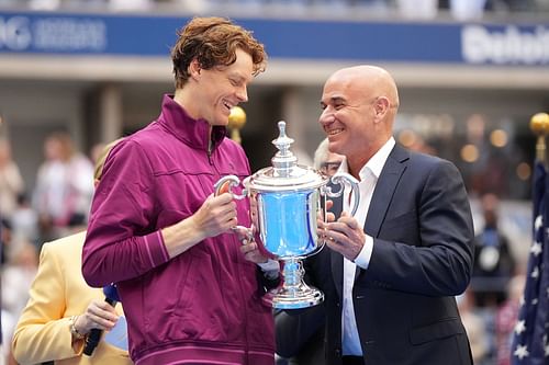 Jannik Sinner (L) being presented with the 2024 US Open men's singles trophy by Andre Agassi (R) (Source: Getty)