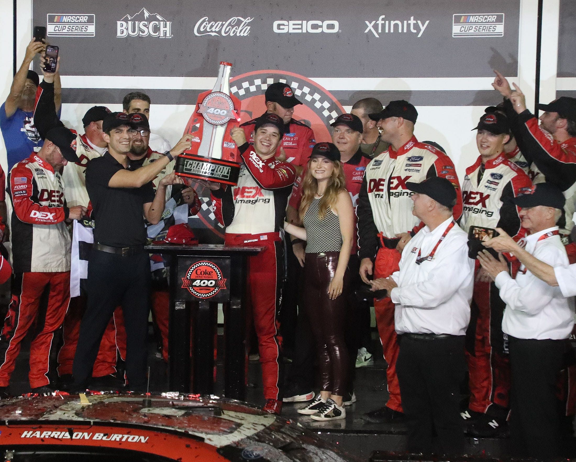 Harrison Burton lifts his trophy in Victory Lane, Saturday August 24, 2024 after winning the Coke Zero Sugar 400 at Daytona International Speedway. Source: Imagn