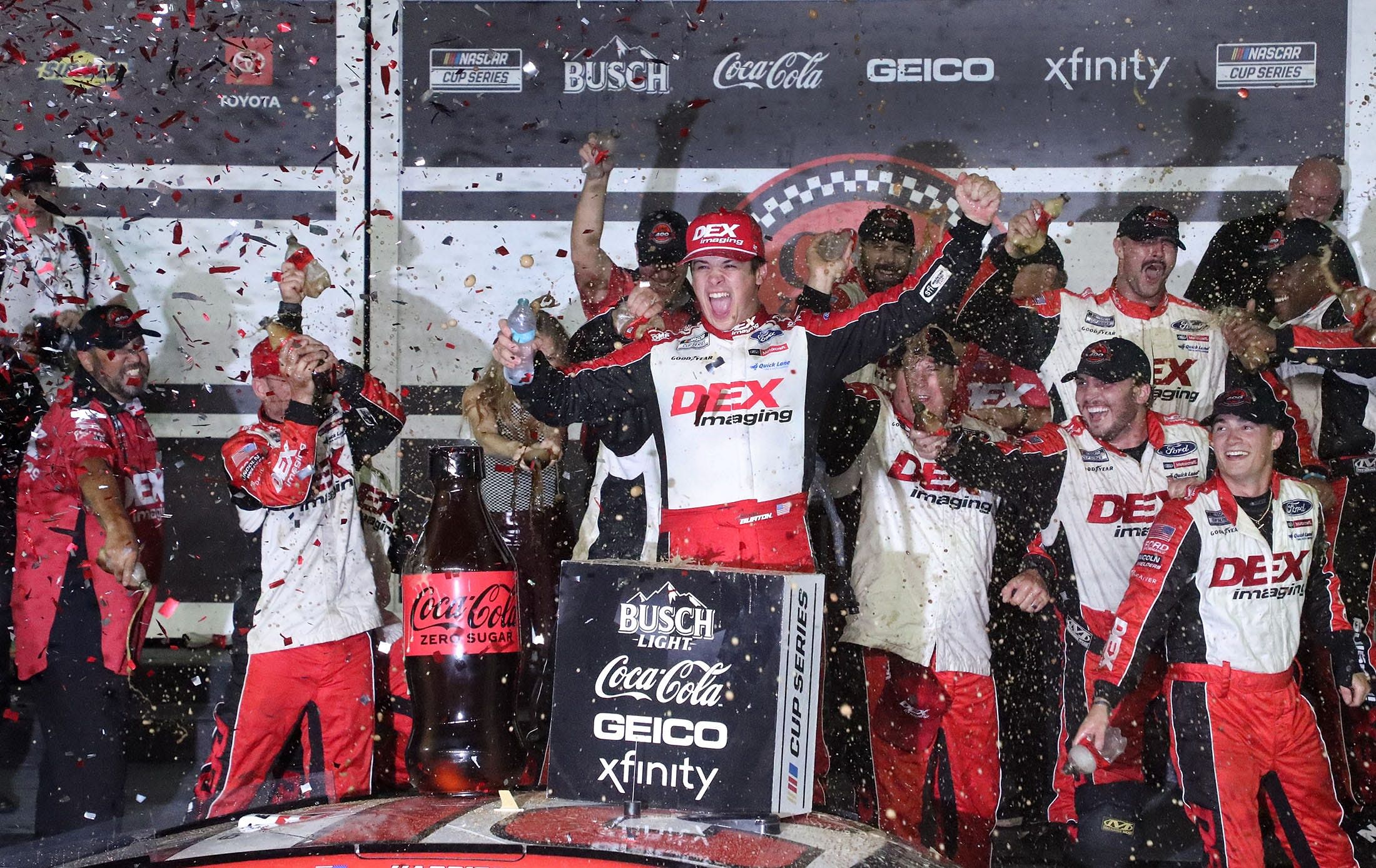 Harrison Burton climbs out of the No. 21 Ford as his crew showers him with Coke Zero Sugar in Victory. Source: Imagn