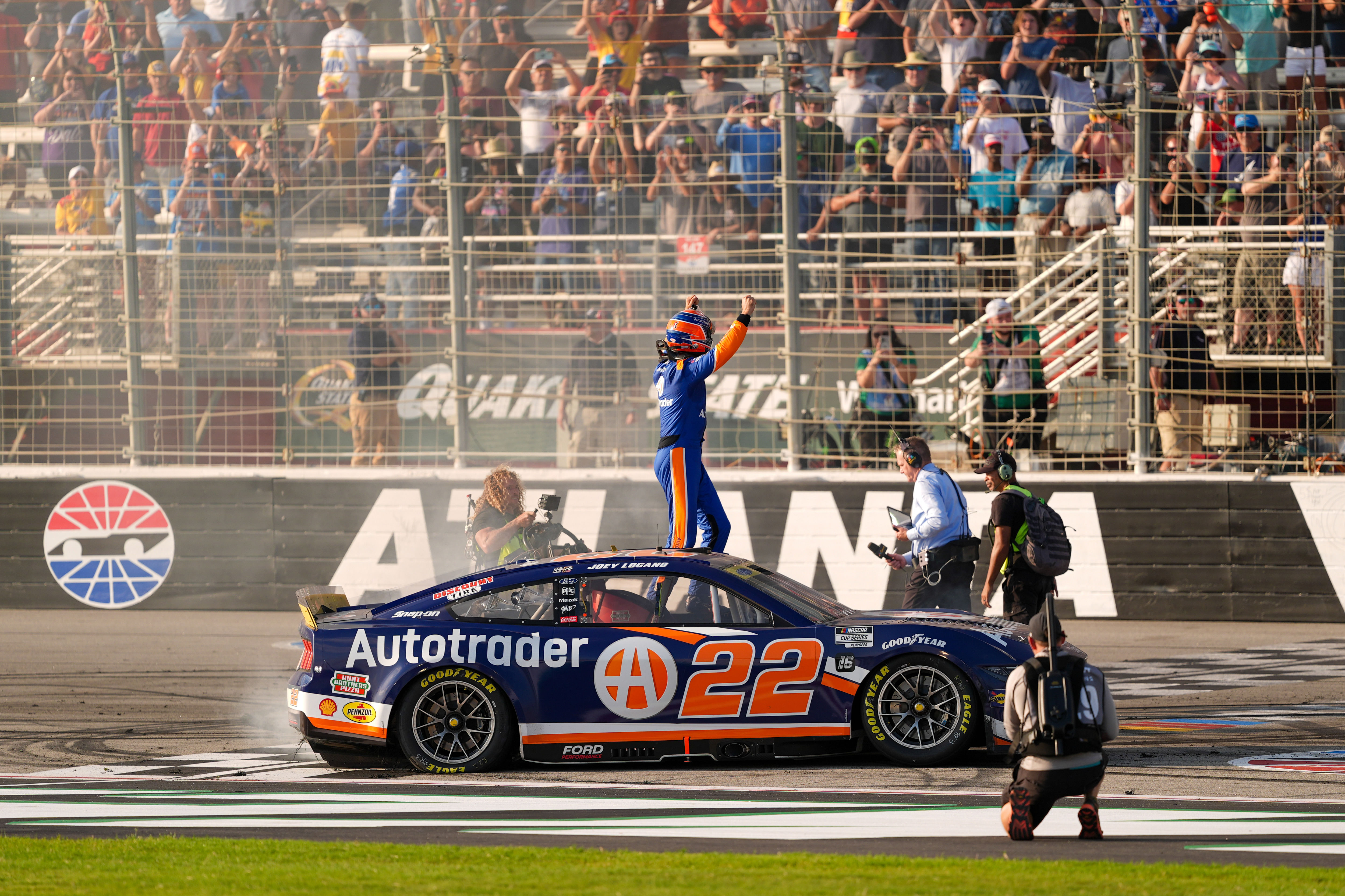 Joey Logano (22) stands on his car as the crowd cheers to celebrate his win at Atlanta Motor Speedway. Mandatory Credit: Jason Allen-Imagn Images