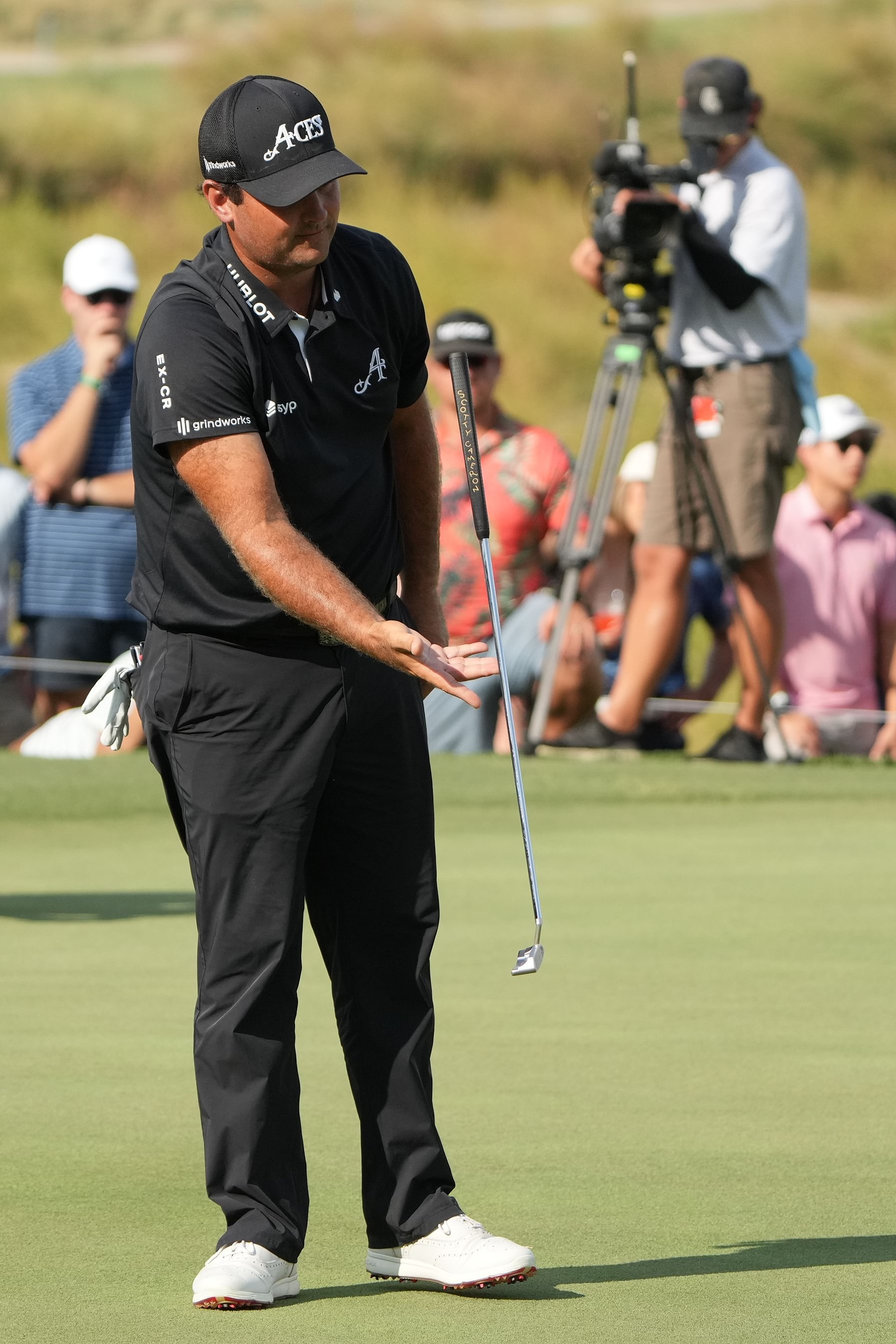 Sep 22, 2024; Carrolton, Texas, USA; Patrick Reed of the 4Aces GC flips his putter in the air after missing a putt on the 18th green during the LIV Golf Dallas Team Championship Finals at Maridoe Golf Club. Mandatory Credit: Jim Cowsert-Imagn Images