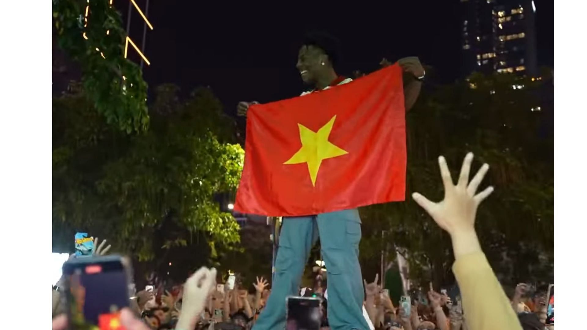 An image of IShowSpeed holding up the Vietnamese flag amidst a sea of fans (Image via IShowSpeed/YouTube)