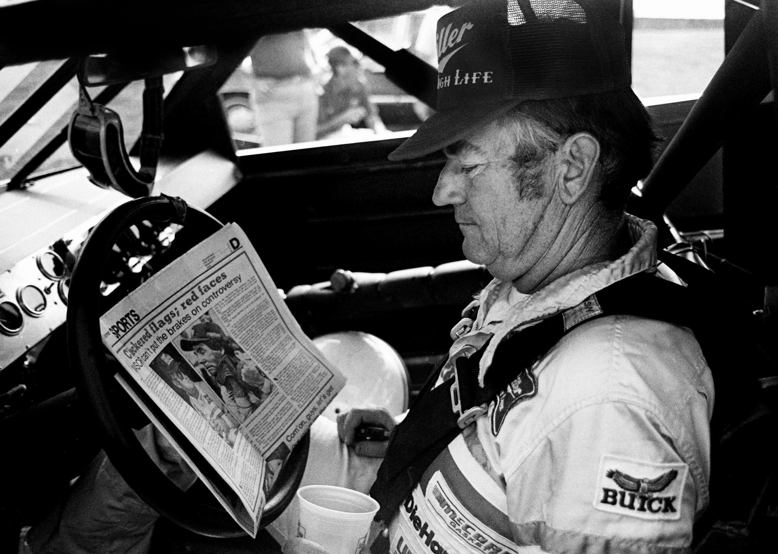 Bobby Allison checks out the newspaper during qualifying trials for the Nashville Pepsi 420 NASCAR Grand National race at Nashville International Raceway on July 13, 1984. Credit: Imagn