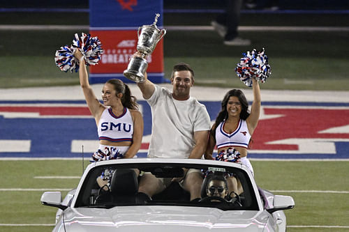  Bryson DeChambeau rides onto the field in a Mustang car with two SMU cheerleaders and the US Open trophy  - Source: Imagn