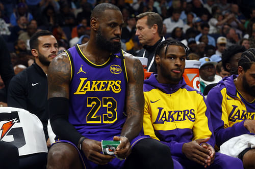 LeBron and Bronny James sit together during a game (Image via Imagn)