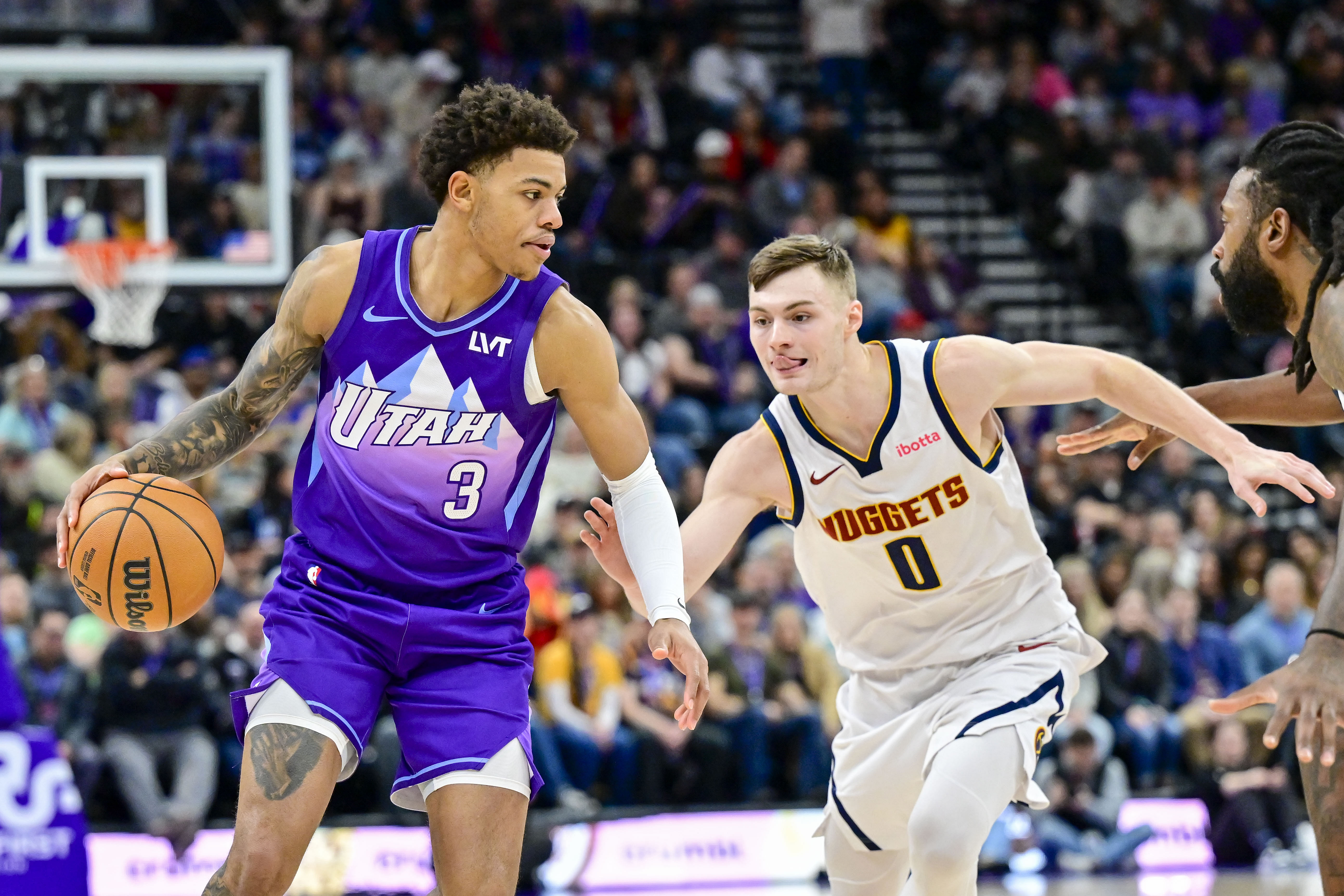 Jazz guard Keyonte George dribbles around Denver Nuggets guard Christian Braun at the Delta Center. Photo Credit: Imagn