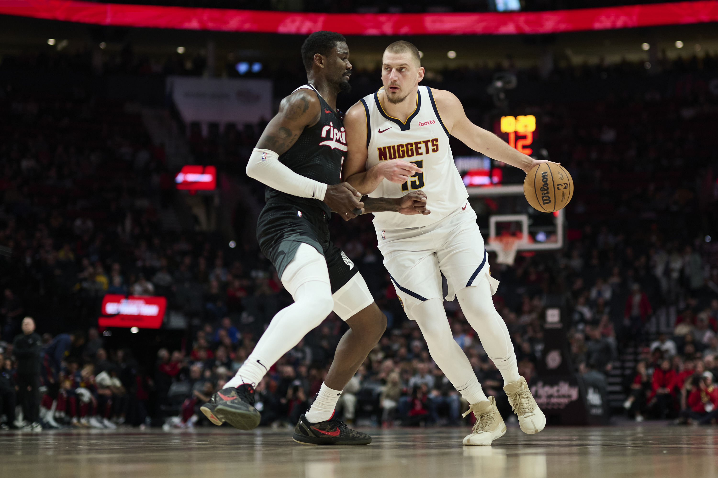 Denver Nuggets center Nikola Jokic (15) dribbles the ball during the second half against Portland Trail Blazers center Deandre Ayton (2) at Moda Center. Mandatory Credit: Troy Wayrynen- Imagn