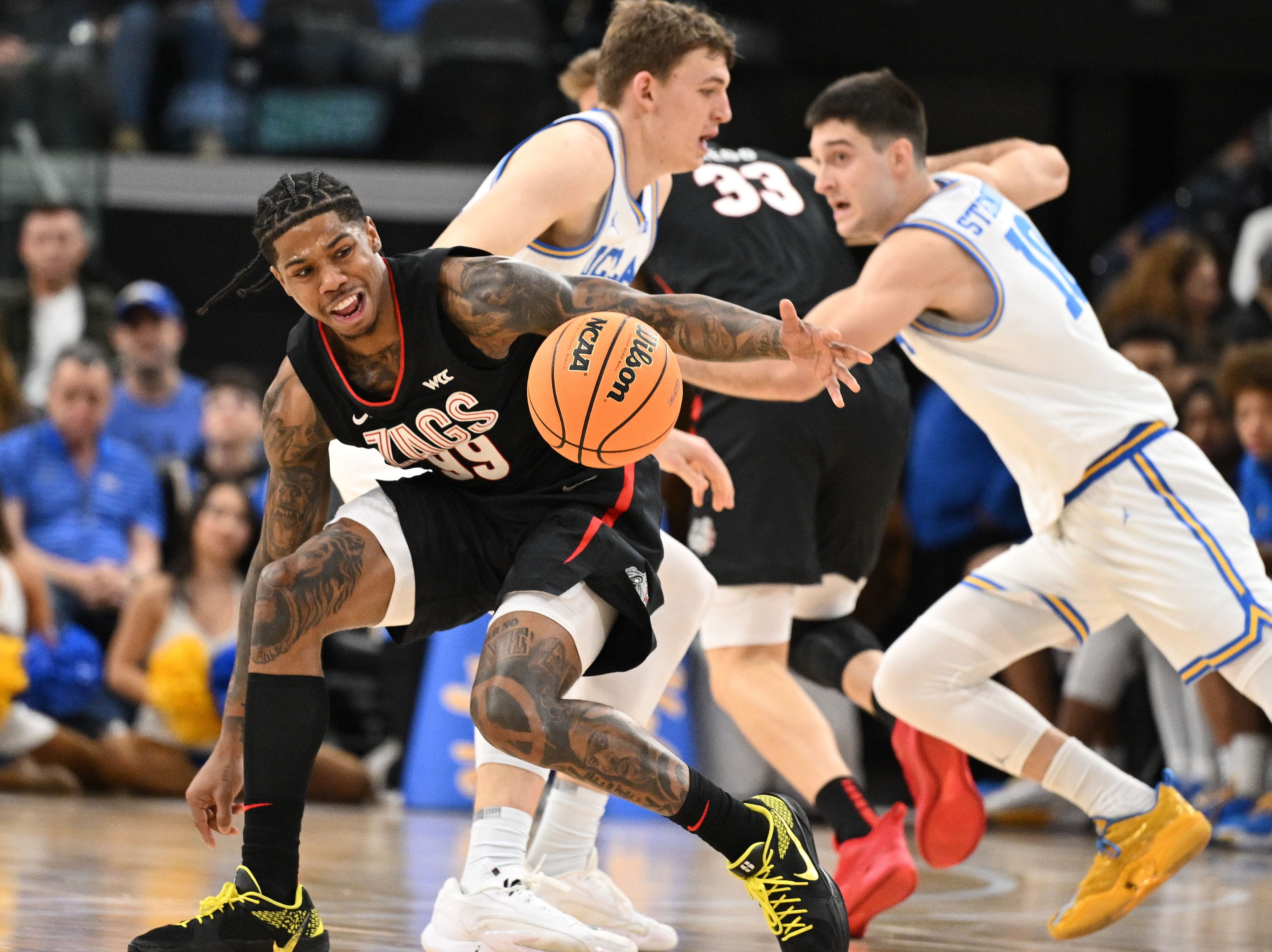 Gonzaga Bulldogs guard Khalif Battle (#99) grabs a loose ball in front of teammate Ben Gregg (#33) and UCLA Bruins forward Tyler Bilodeau (#34) and guard Lazar Stefanovic (#10) during the first half of their NCAA game at Intuit Dome (Credits: IMAGN)