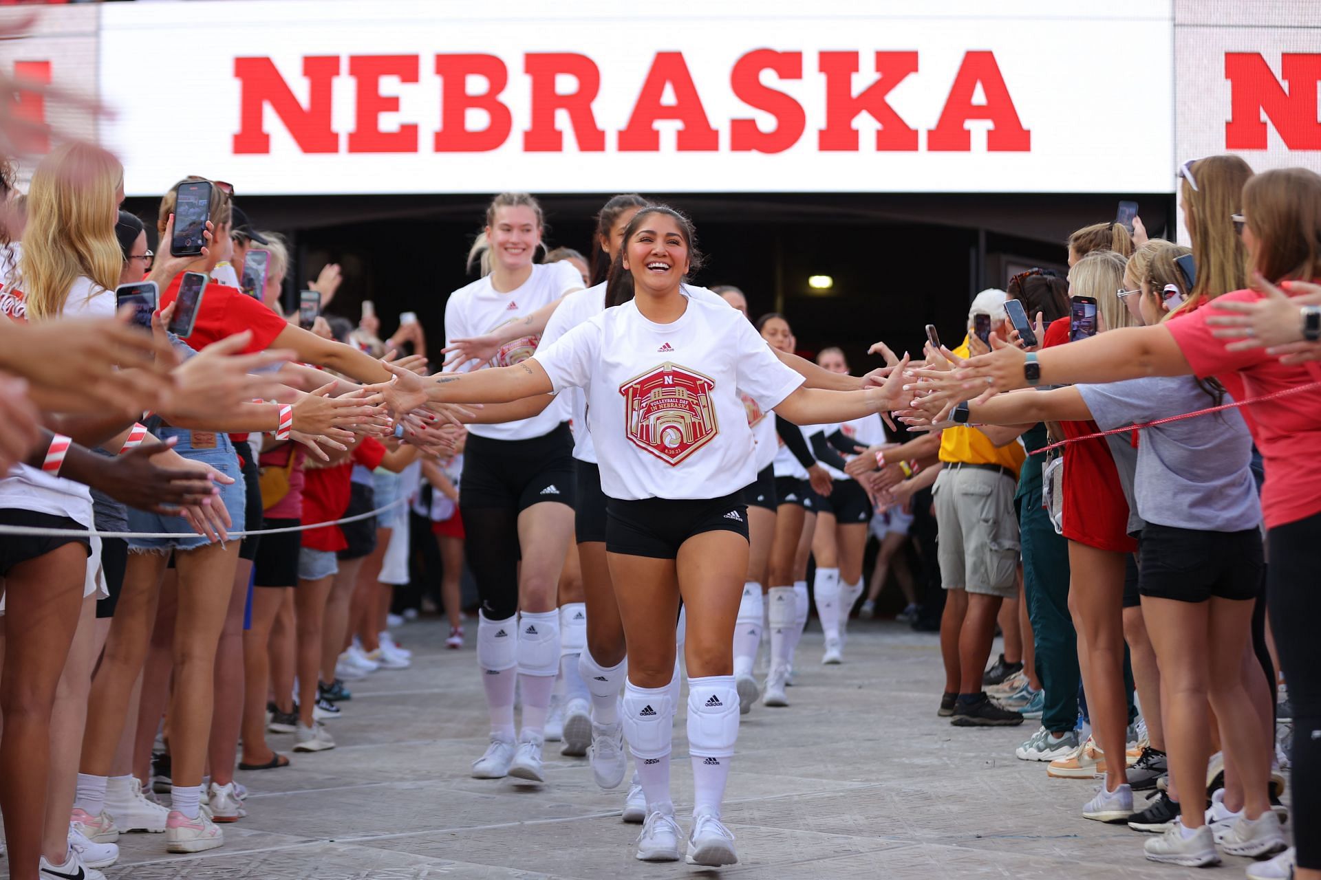 Rodriguez donning a white t-shirt as she high-fives the Nebraska fans before their match against Omaha Mavericks (Image via: Getty Images)