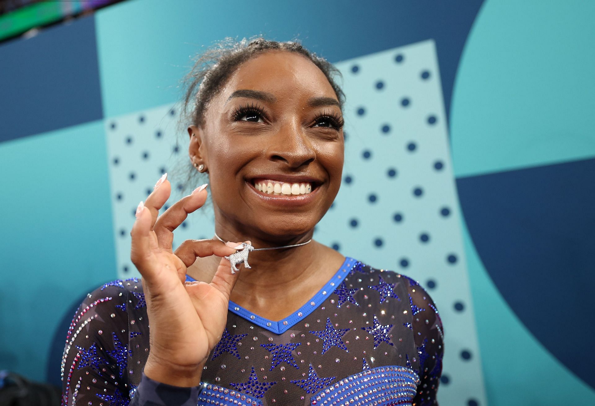 Simone Biles poses with necklace in the likeness of a goat at Paris Olympics (Photo by Jamie Squire/Getty Images)