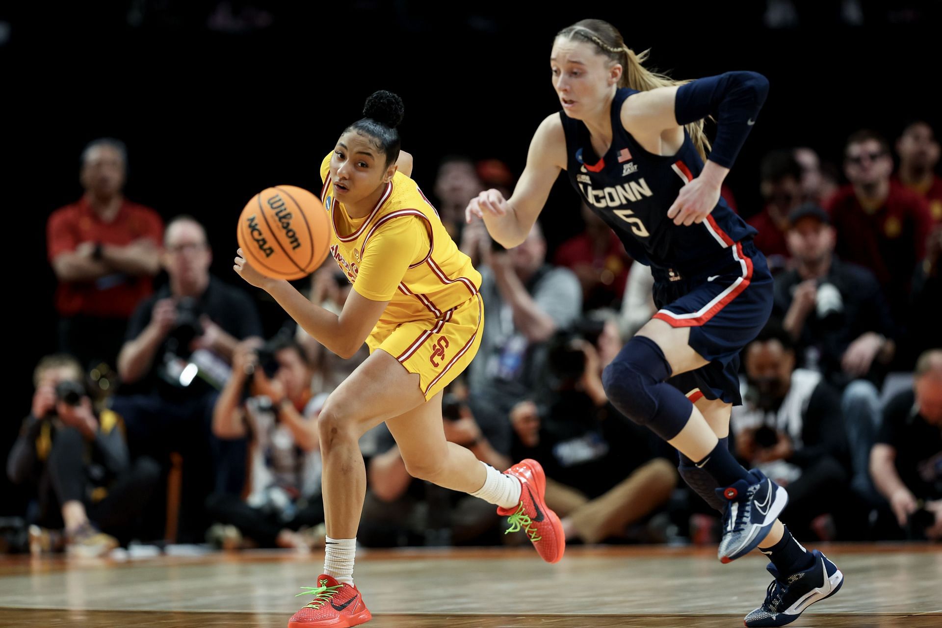 JuJu Watkins (#12) of the USC Trojans and Paige Bueckers (#5) of the UConn Huskies chase after a loose ball during the second half of their Elite Eight clash. Photo: Getty