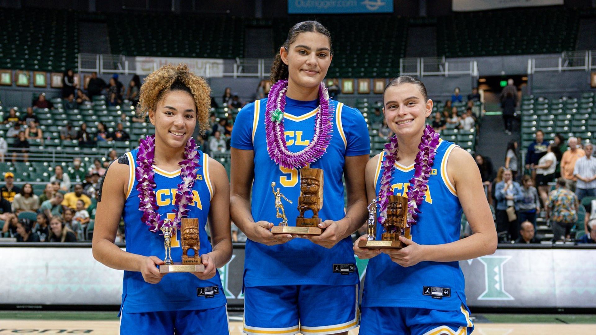 (L-R) Kiki Rice, Lauren Betts, and Gabriela Vasquez receiving trophies for the Rainbow Wahine Showdown. (Image Credits: @UCLAWBB on X)