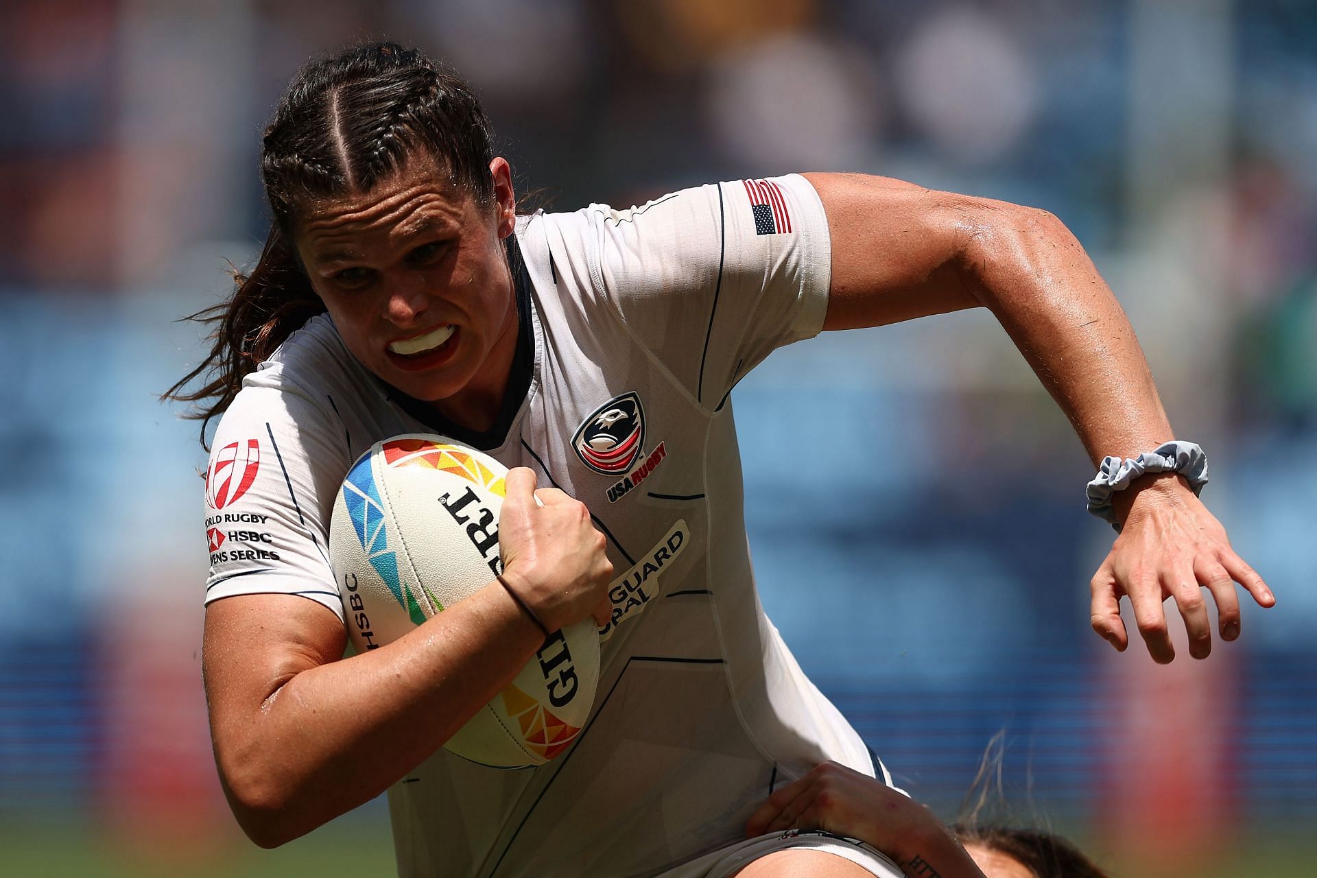 Maher running with the rugby ball donning a white jersey during the United States and Great Britain match (Image via: Getty Images)