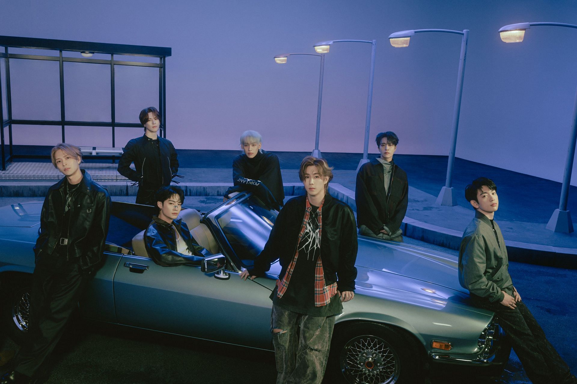 Got7 members surrounding a car and staring at the camera