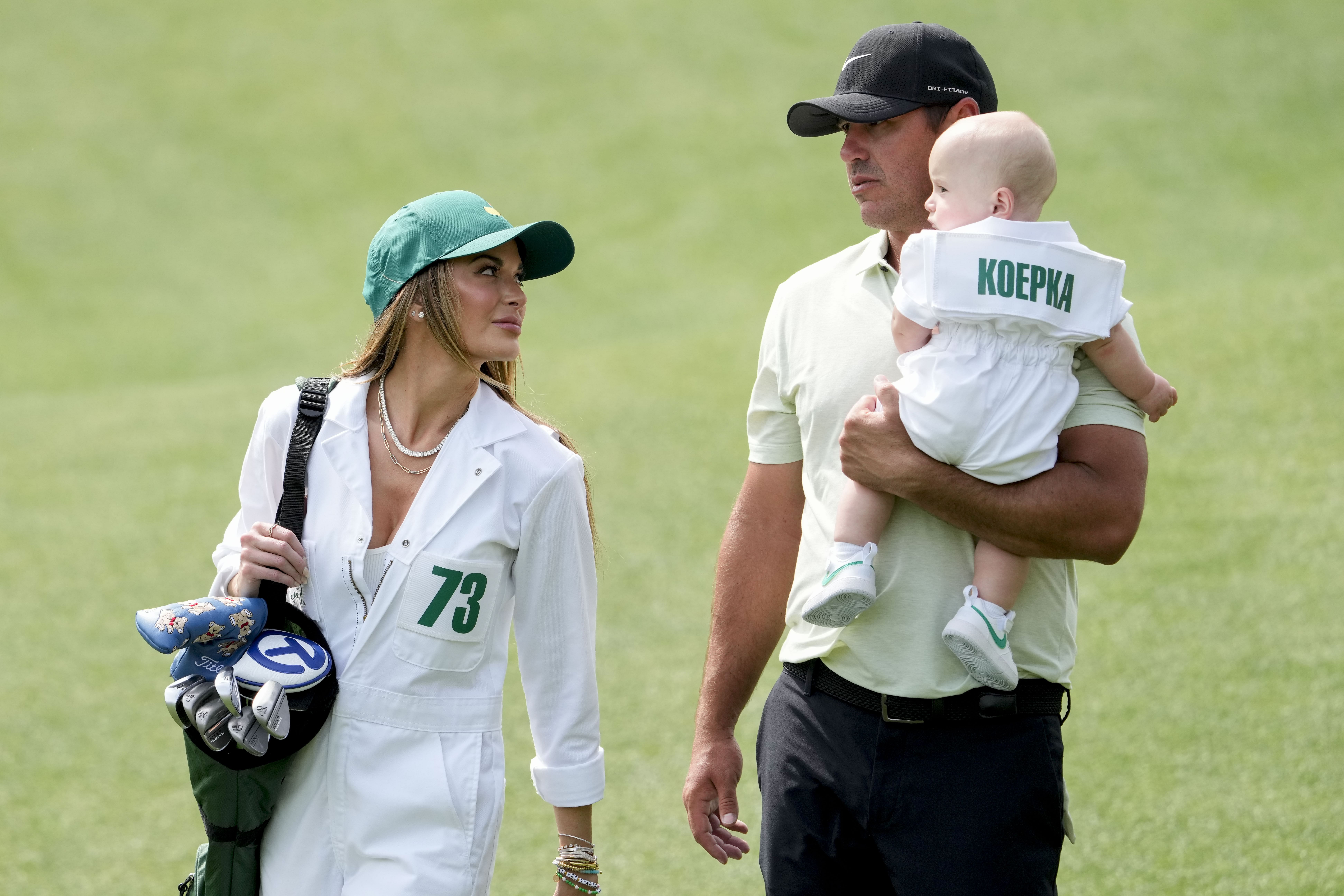 Brooks Koepka carries his son, Crew, with his wife, Jena Sims, during the Par 3 Contest at Augusta National Golf Club. (Credit: Michael Madrid-USA TODAY Network)