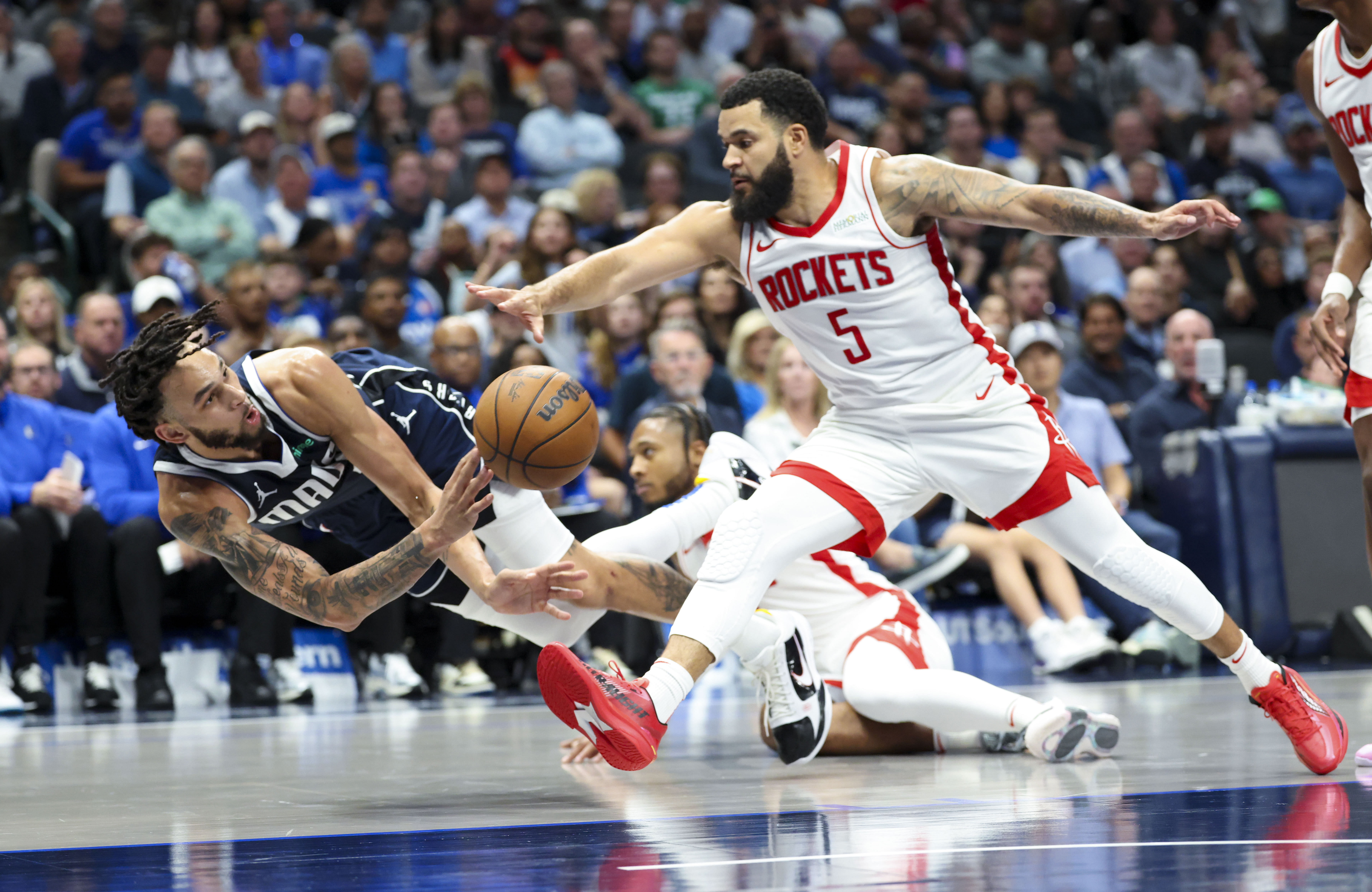 Dallas Mavericks center Dereck Lively II dives to save a ball as Houston Rockets guard Fred VanVleet defends at American Airlines Center. Photo Credit: Imagn