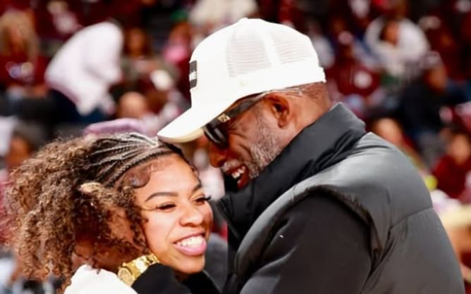 Coach Prime shares an inside joke with daughter Shelomi Sanders after visiting her courtside