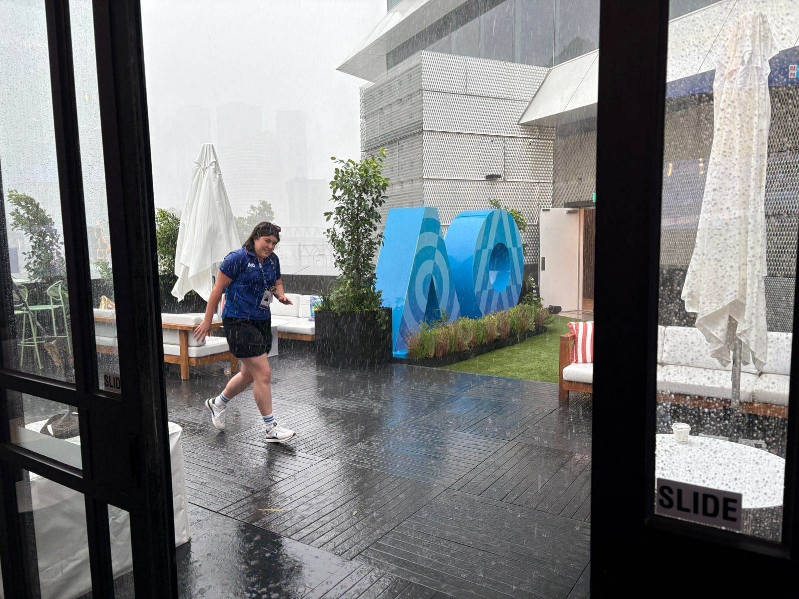 An Australian Open staff member braves the rain to work.