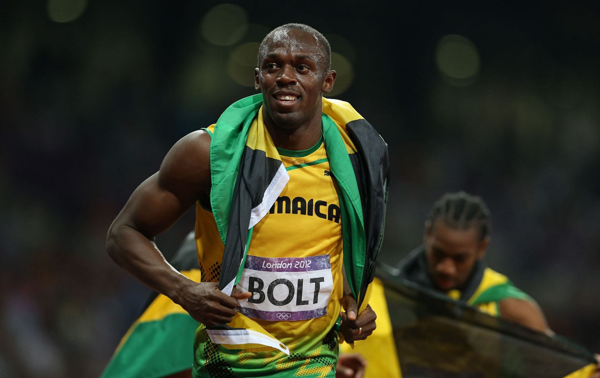 Usain Bolt celebrating his win with the Jamaican flag - (Source: Getty)