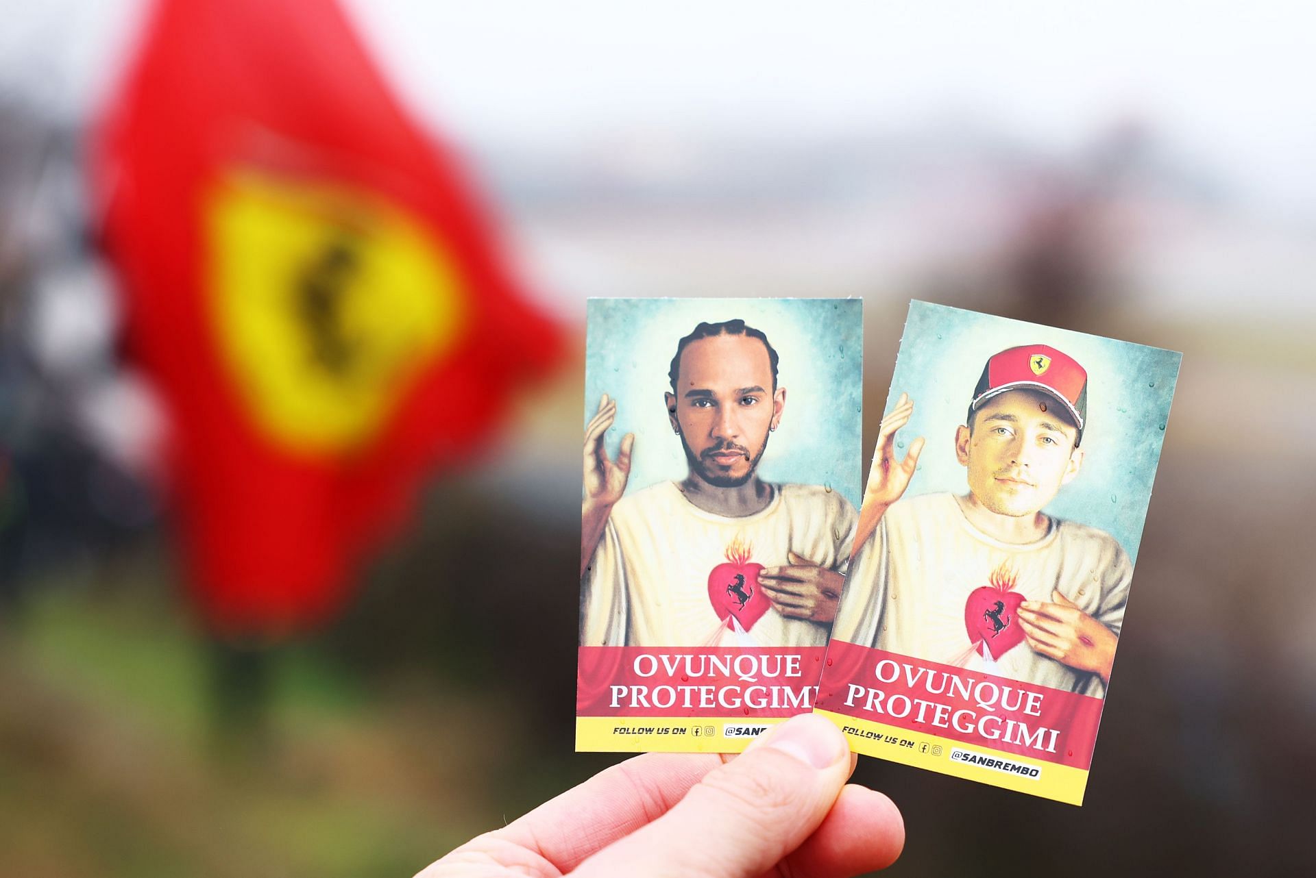 A fan holds cards with the faces of Lewis Hamilton and Charles Leclerc during Hamilton&#039;s first official days as a Scuderia Ferrari F1 driver - Source: Getty