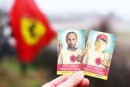 A fan holds cards with the faces of Lewis Hamilton and Charles Leclerc during Hamilton's first official days as a Scuderia Ferrari F1 driver - Source: Getty