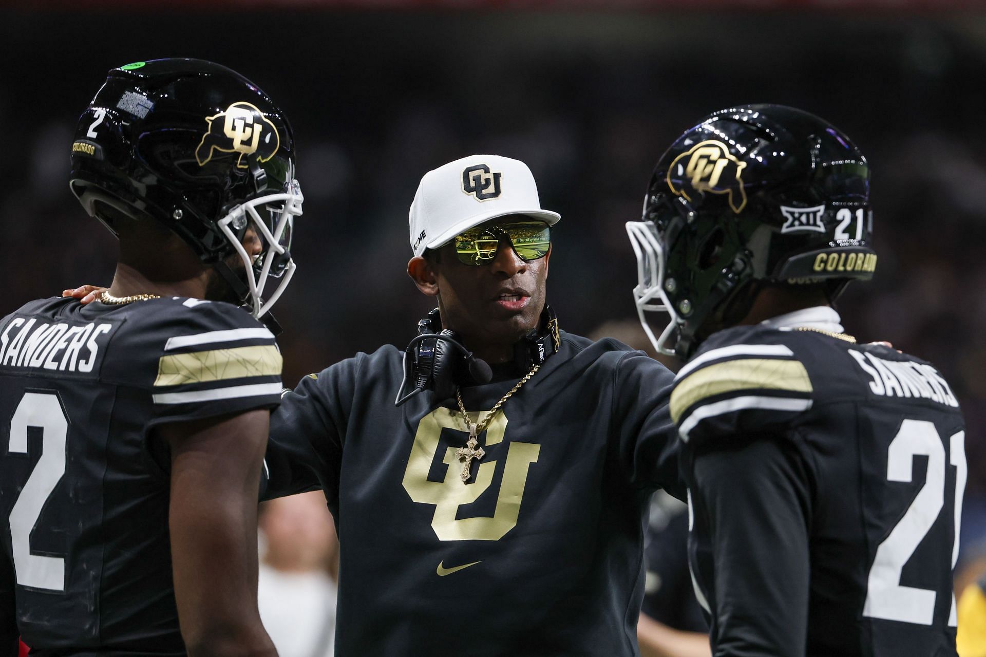 Colorado Buffaloes head coach Deion Sanders talks to Colorado Buffaloes quarterback Shedeur Sanders (2) and Colorado Buffaloes safety Shilo Sanders (21). (Credits: Getty)