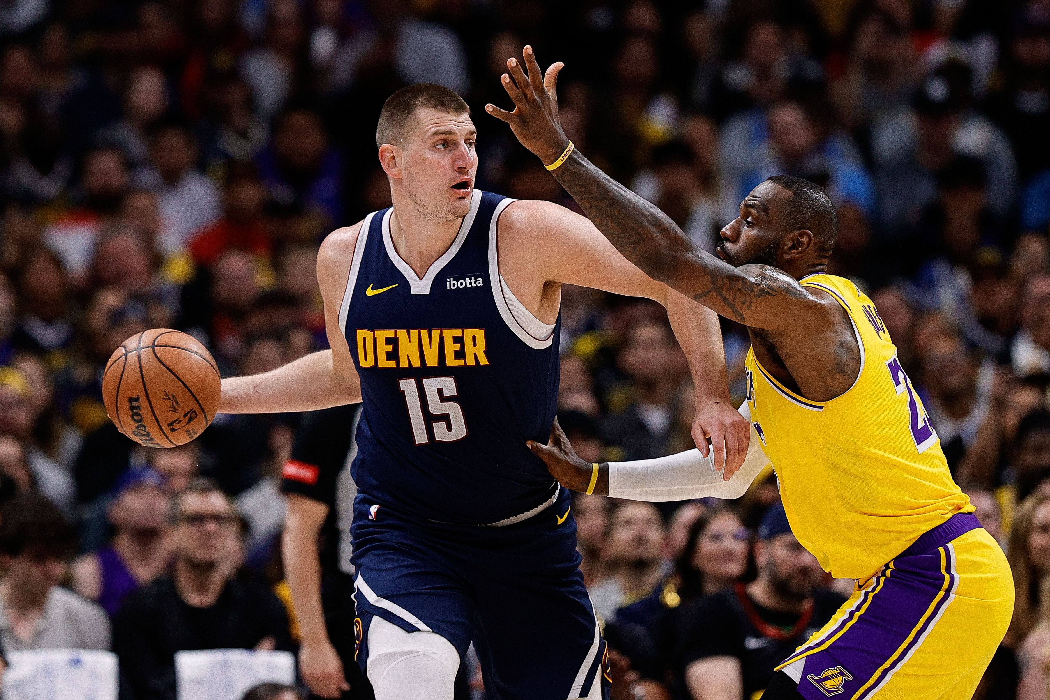 Nikola Jokic controls the ball under pressure from LeBron James at Ball Arena. Photo Credit: Imagn