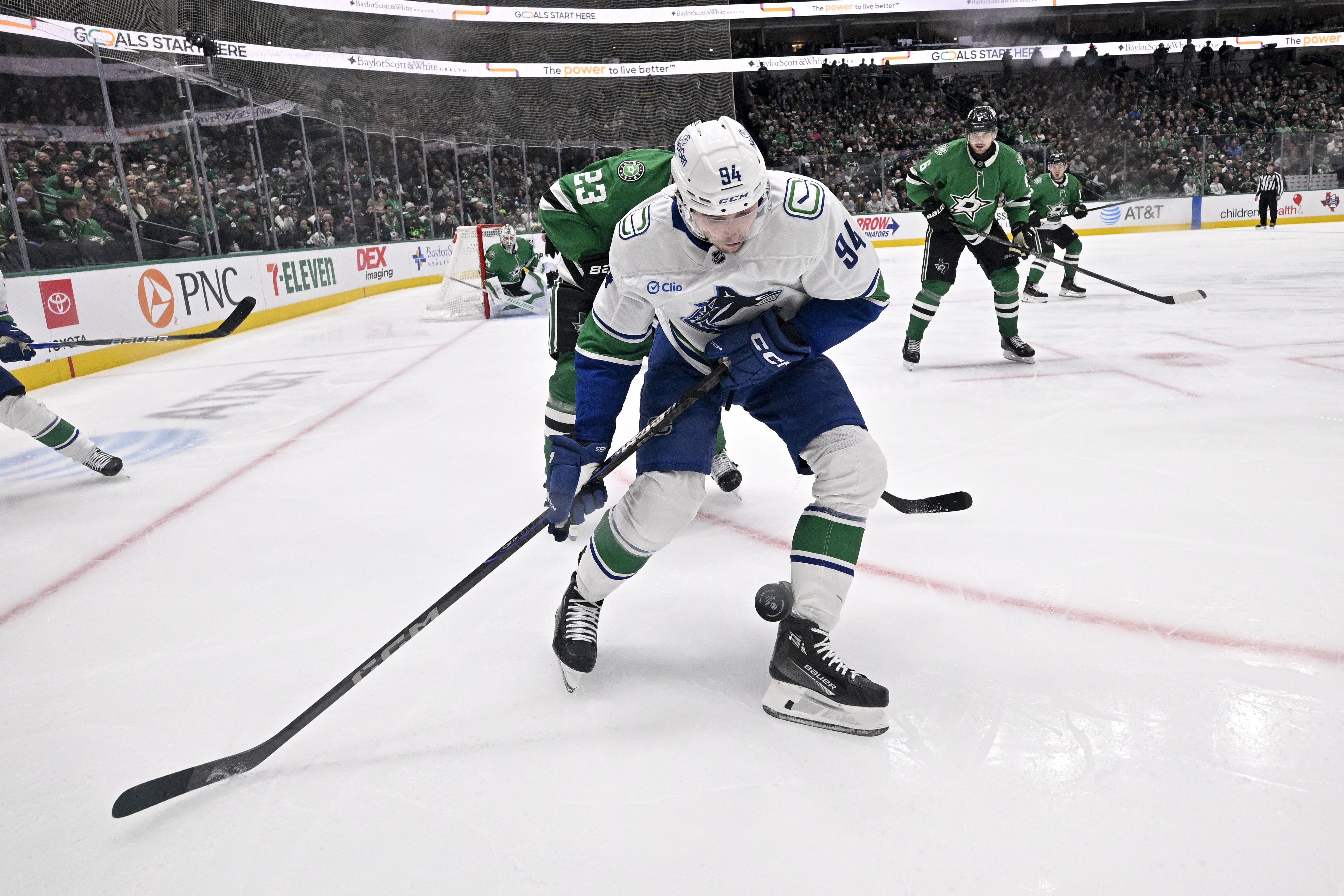 Jan 31, 2025; Dallas, Texas, USA; Dallas Stars defenseman Esa Lindell (23) and Vancouver Canucks center Linus Karlsson (94) chase the puck in the Stars zone during the third period at the American Airlines Center. Mandatory Credit: Jerome Miron-Imagn Images - Source: Imagn