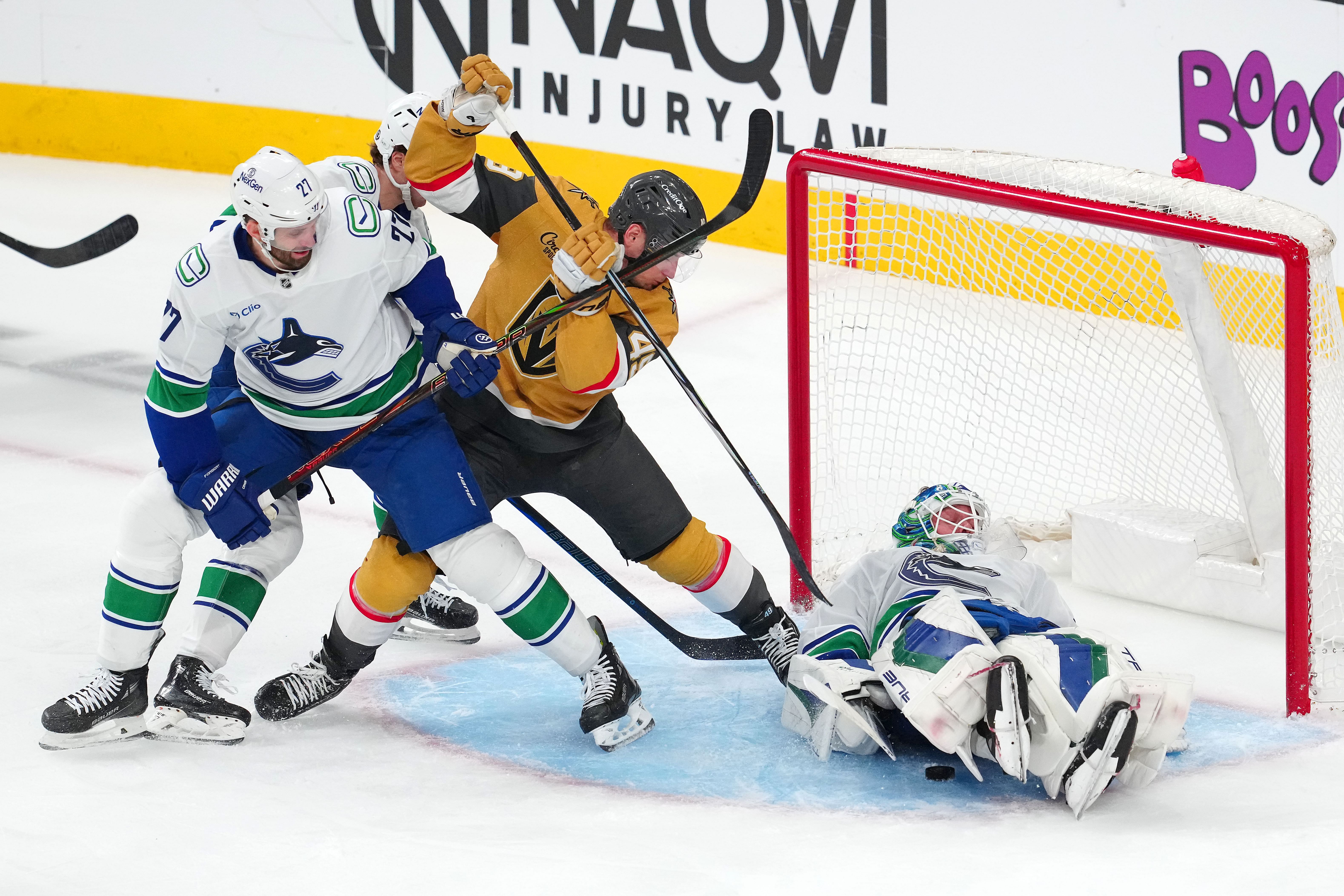 Feb 22, 2025; Las Vegas, Nevada, USA; Vancouver Canucks goaltender Kevin Lankinen (32) covers the puck as Vancouver Canucks defenseman Derek Forbort (27) attempts to tie up Vegas Golden Knights center Ivan Barbashev (49) during the third period at T-Mobile Arena. Mandatory Credit: Stephen R. Sylvanie-Imagn Images - Source: Imagn