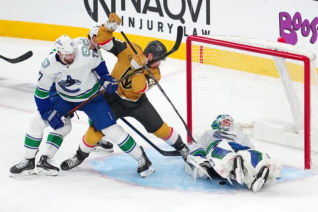 Feb 22, 2025; Las Vegas, Nevada, USA; Vancouver Canucks goaltender Kevin Lankinen (32) covers the puck as Vancouver Canucks defenseman Derek Forbort (27) attempts to tie up Vegas Golden Knights center Ivan Barbashev (49) during the third period at T-Mobile Arena. Mandatory Credit: Stephen R. Sylvanie-Imagn Images - Source: Imagn