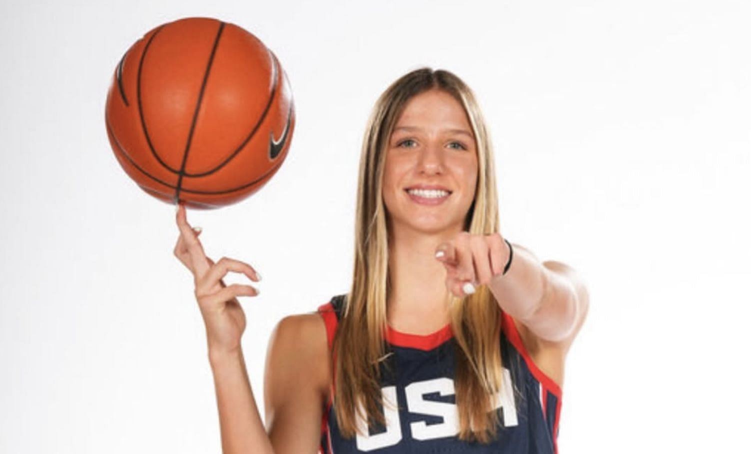 Addison Bjorn, wearing a red USA Basketball jersey, smiles while spinning a ball