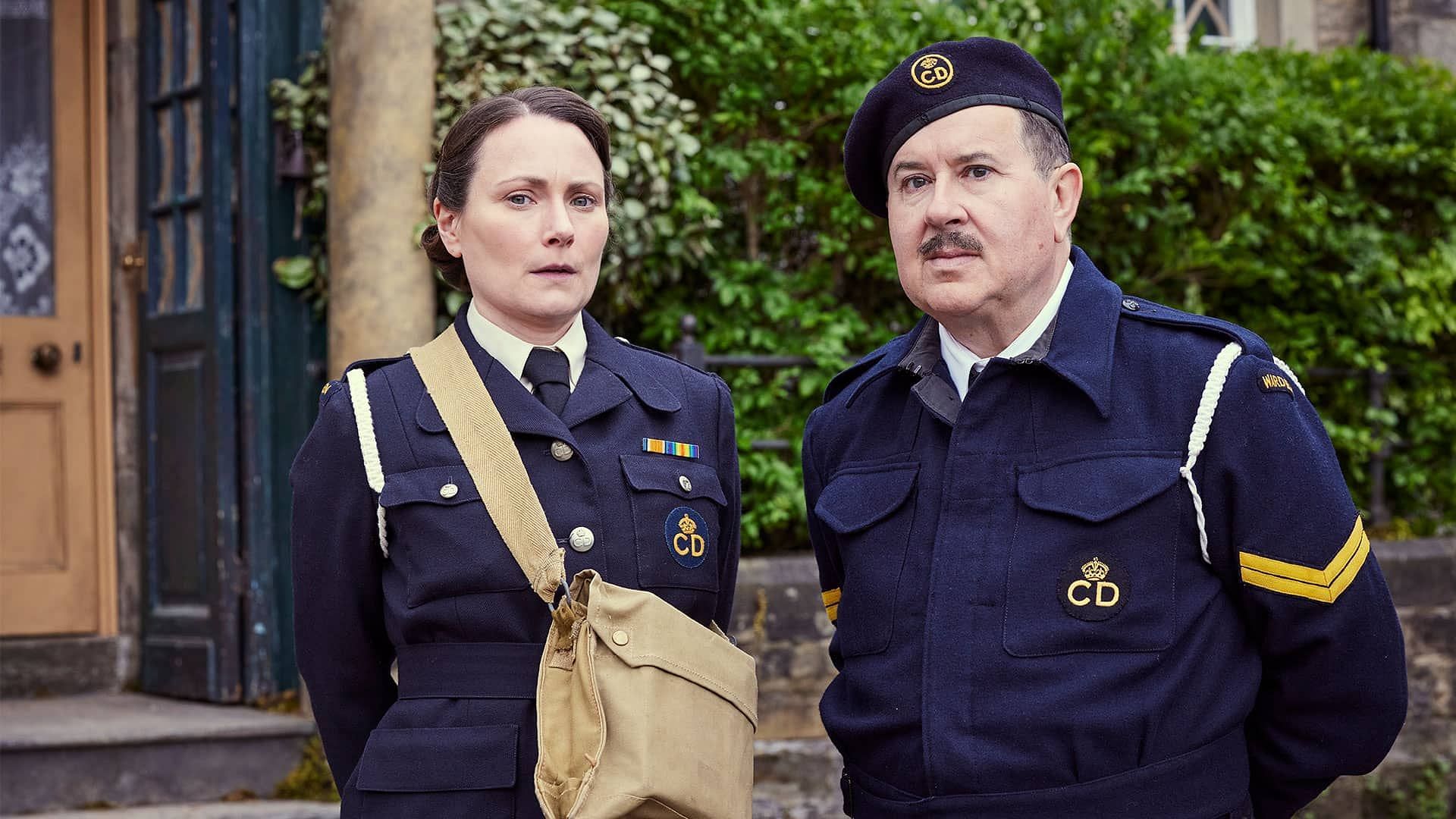 Anna Madeley as Mrs. Hall and Jeremy Swift as Mr. Bosworth in their ARP uniforms, showcasing their commitment to the village&rsquo;s wartime efforts in All Creatures Great and Small (Image via PBS)