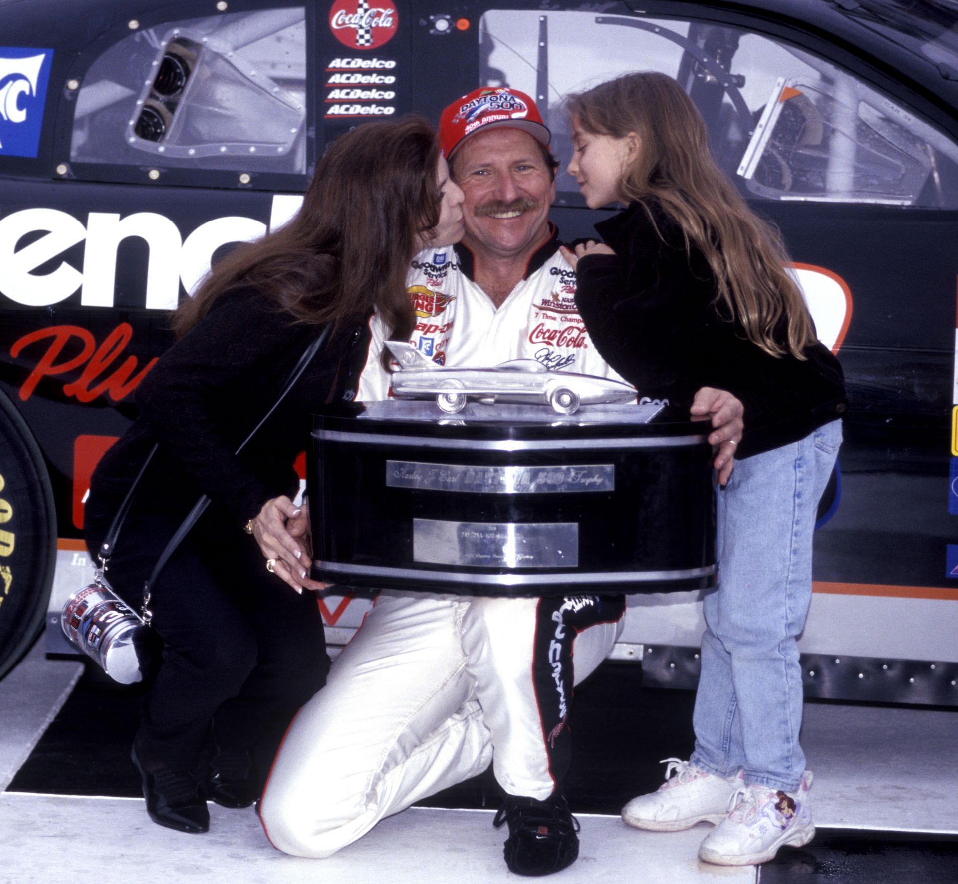 Dale Earnhardt victorious, holding trophy and getting kisses from wife Teresa and daughter Taylor after winning the 1998 Daytona 500 - Source: Getty