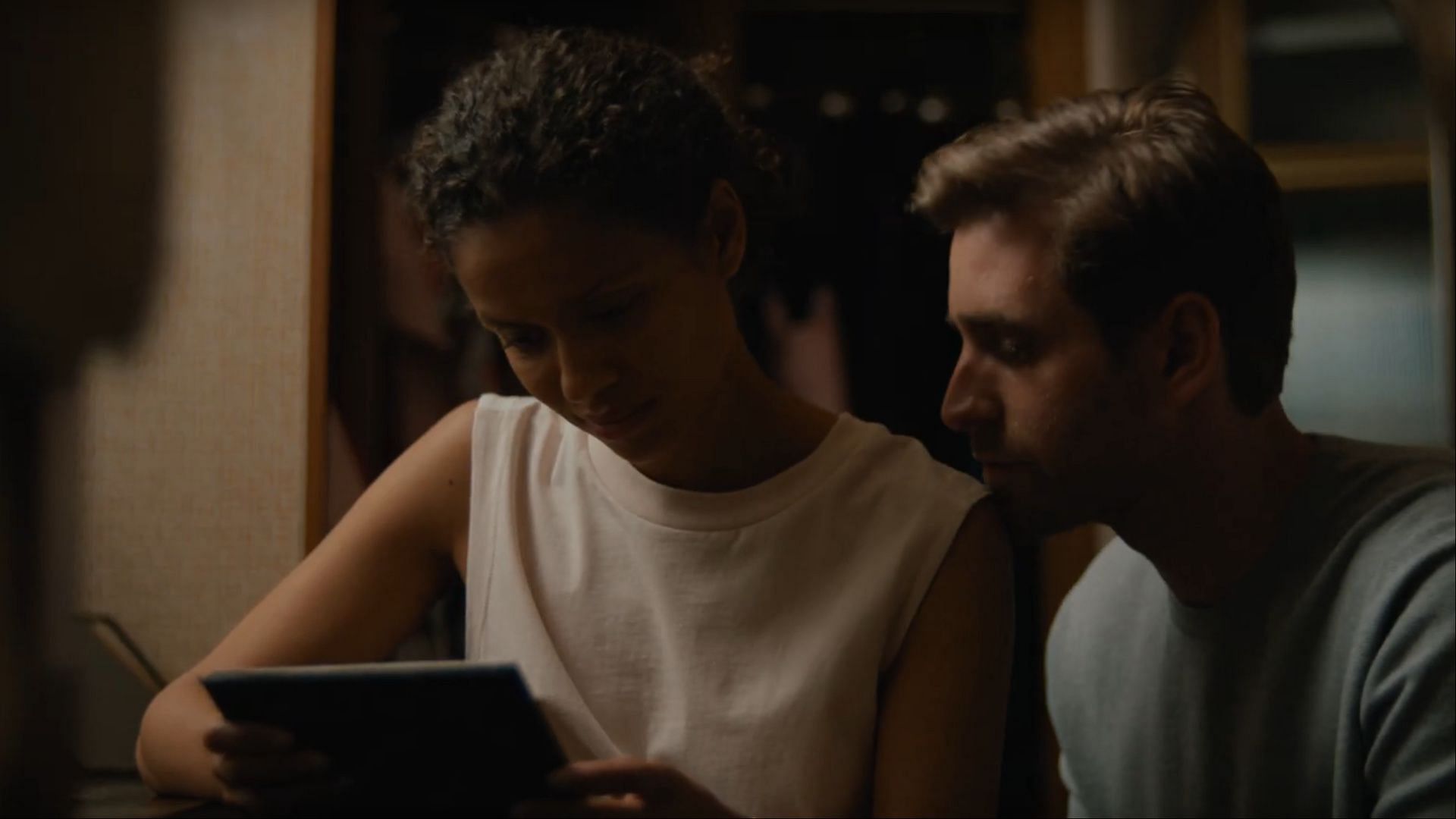 Sophie (Gugu Mbatha-Raw) and her husband, James Ellis (Oliver Jackson-Cohen), look through an old photo. This scene in Surface season 1 highlights the cracks in their relationship as Sophie begins to uncover James&rsquo;s secrets. (Image via AppleTV+/Youtube)