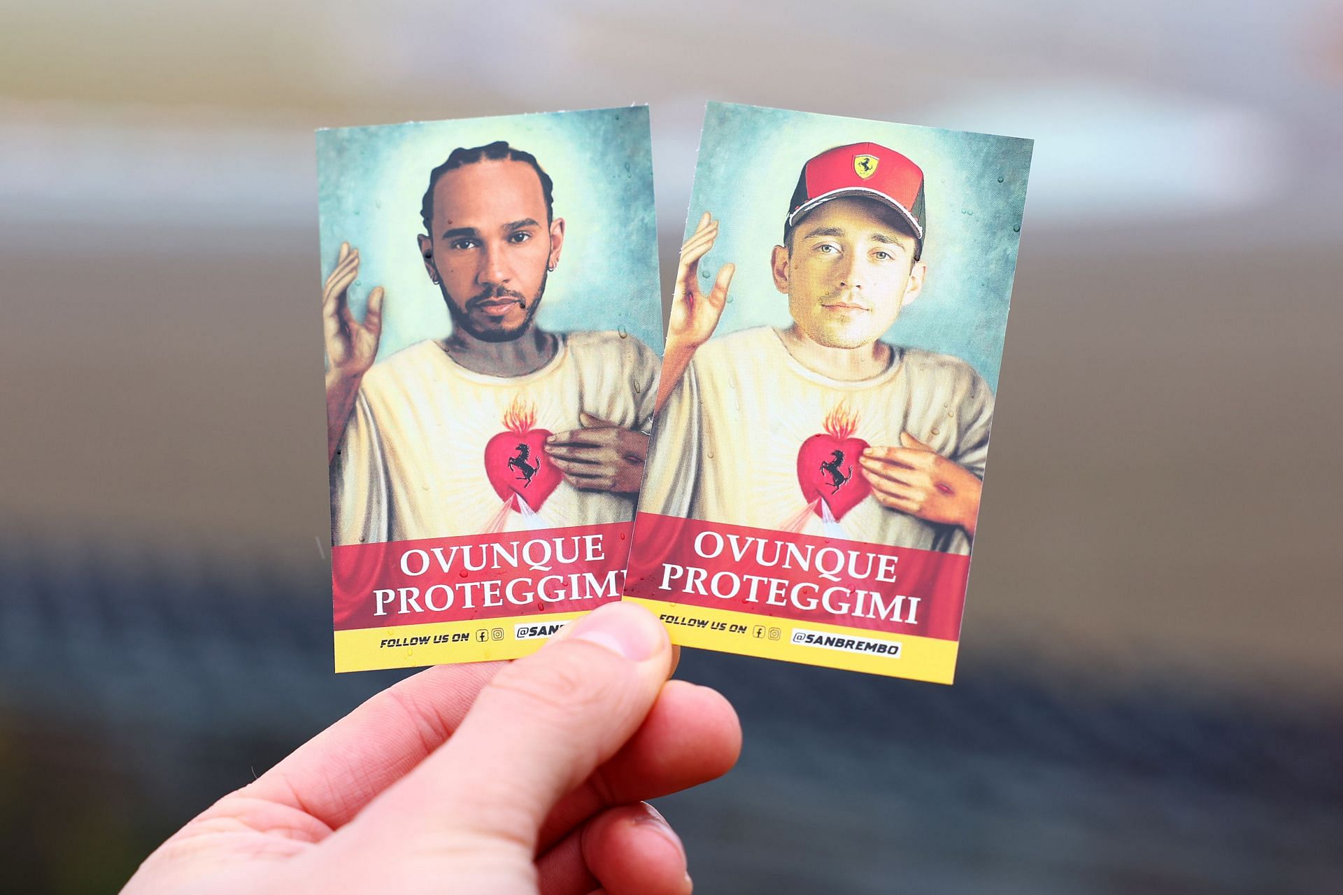 A fan holds cards with the faces of Lewis Hamilton of Great Britain and Ferrari and Charles Leclerc of Monaco and Ferrari during Lewis Hamilton