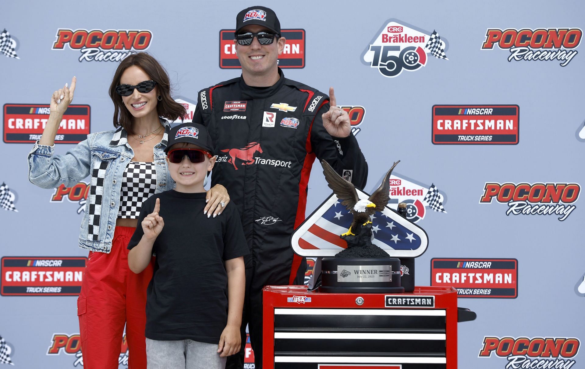 LONG POND, PENNSYLVANIA - JULY 22: Kyle Busch, driver of the #51 Zariz Transport Chevrolet, celebrates with wife, Samantha Busch, and son, Brexton Busch in victory lane after winning NASCAR Craftsman Truck Series CRC Brakleen 150 and Kyle Busch Motorsports